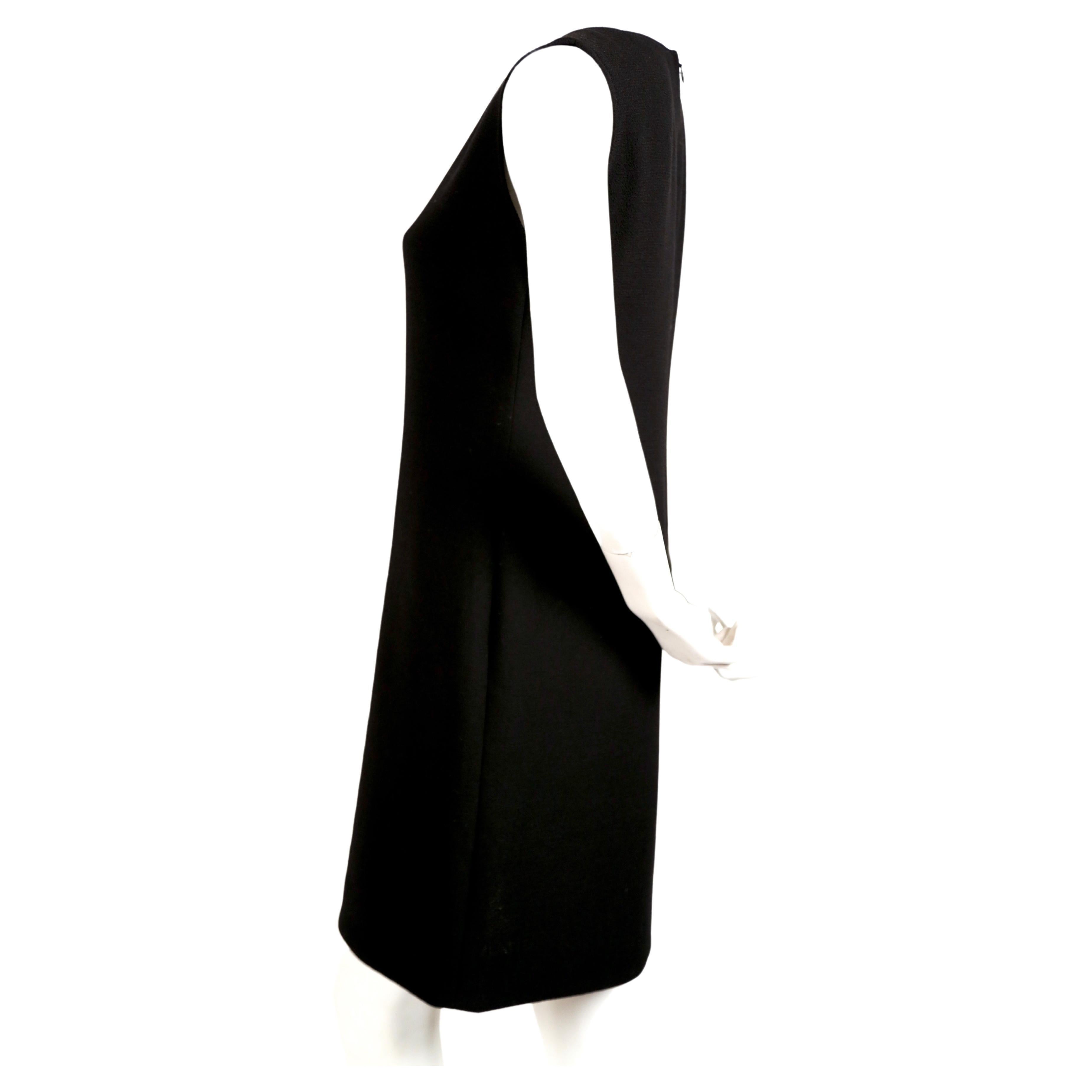 Black wool, haute couture dress with circular cut-outs lined with red wool, designed by Pierre Cardin dating to the late 1960's. Sleek shape falls from the shoulders to the hem skimming the body creating a subtle A-line shape. Fabric is not bulky.