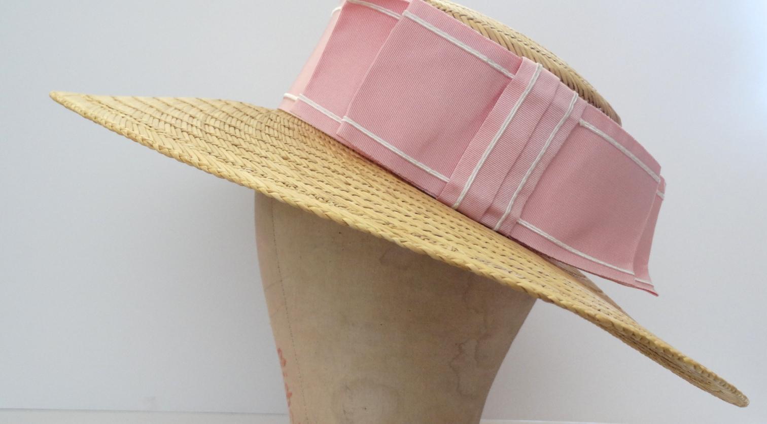 The perfect straw boater to add to your resort-wear wardrobe! Circa 1960s- boasts a large pink grosgrain ribbon bow around the base of the hat. Crafted from a classic yellow woven straw. Pairs perfectly with all your favorite sun dresses or at the