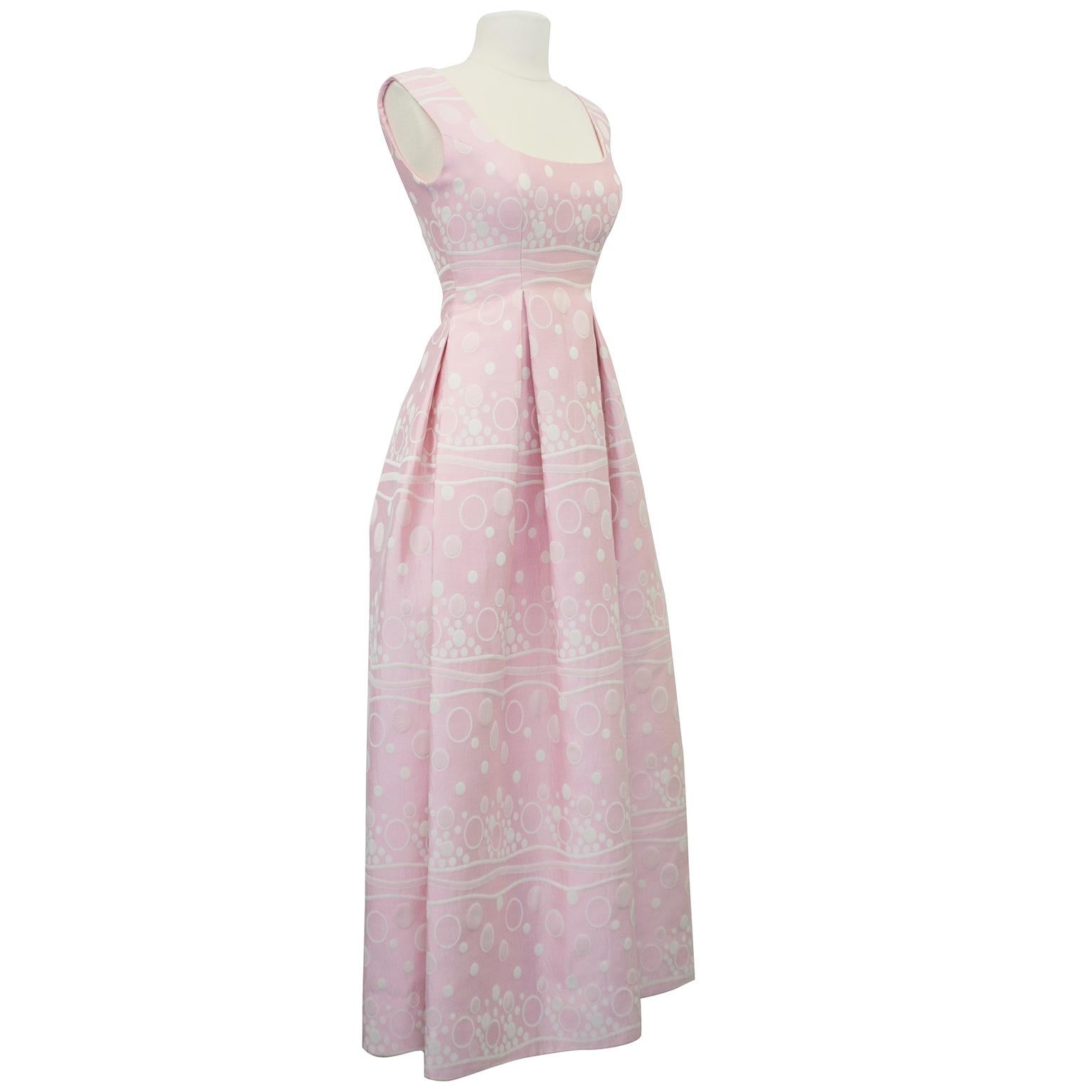 Beautiful and elegant 1960s pink gown with white bubble brocade style print throughout. From the venerable Ester Wolf Boutique in Houston, TX, the gown has a scooped neckline, is fitted through the waist and falls A line to the floor. High back and