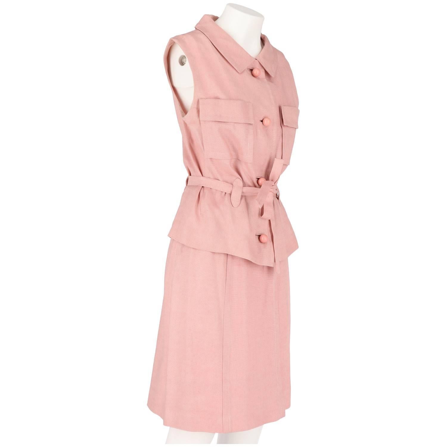 Beautiful two piece tailored suit in pink linen. It features a sleeveless top with thick pink buttons, two patch pockets on the bust and a waistband, and a flared skirt with lateral zip closure and button. The item is vintage, it was produced in the