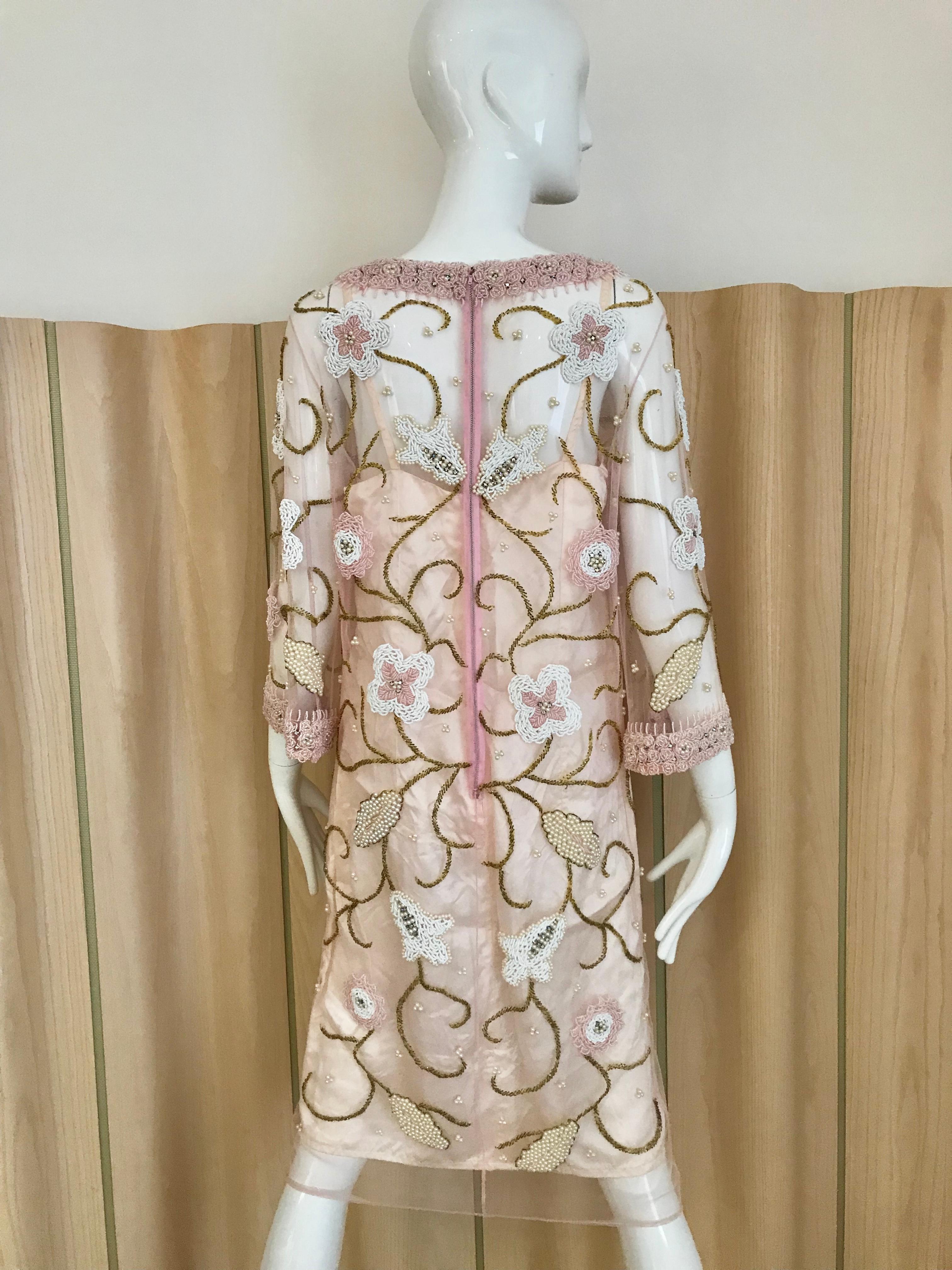 Magnifique tunique vintage des années 60 en maille transparente rose perlée de perles de fleurs blanches, roses et dorées. Le col et les manches sont perlés de perles roses. Parfait pour un cocktail.
La tunique est livrée avec un slip.  
Buste :  38