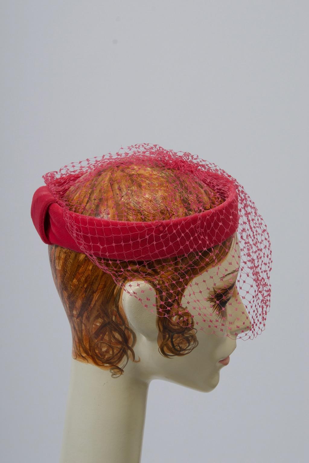 c.1960 fascinator consisting of a structured pink velvet ring under a coordinating deep net that extends from top of head down front and sides.
One size fits all.