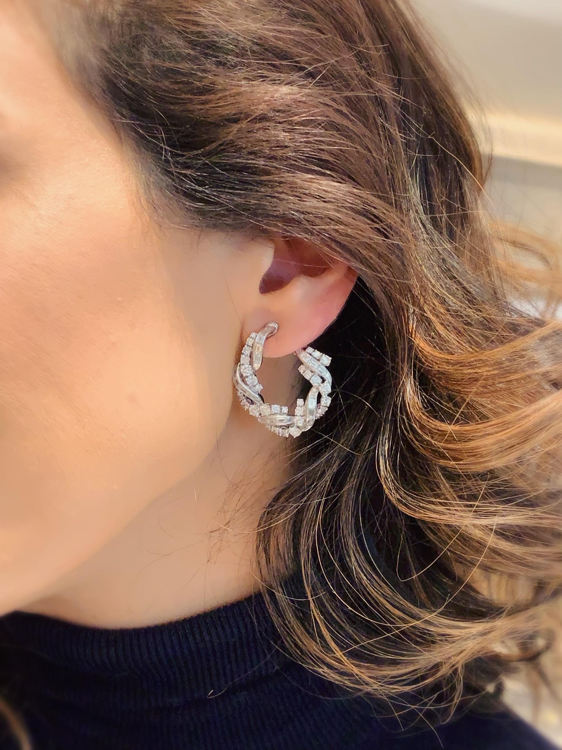 The ever-stylish hoop earring is made magical in these front-facing, mid-20th century sparkling diamond earrings that look like braided strands of light. The interplay of the brilliant round-cut stones with the mirrored baguette-cuts, set in