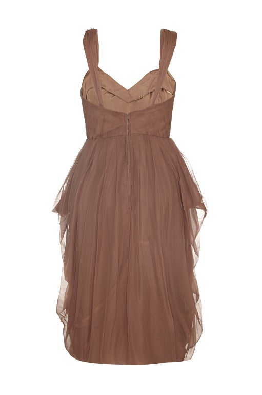 Cette fabuleuse robe de cocktail des années 1960 en mousseline de soie plissée et en taffetas de couleur roussâtre présente une coupe remarquablement innovante et est en très bon état. La robe est composée de taffetas de soie et présente une