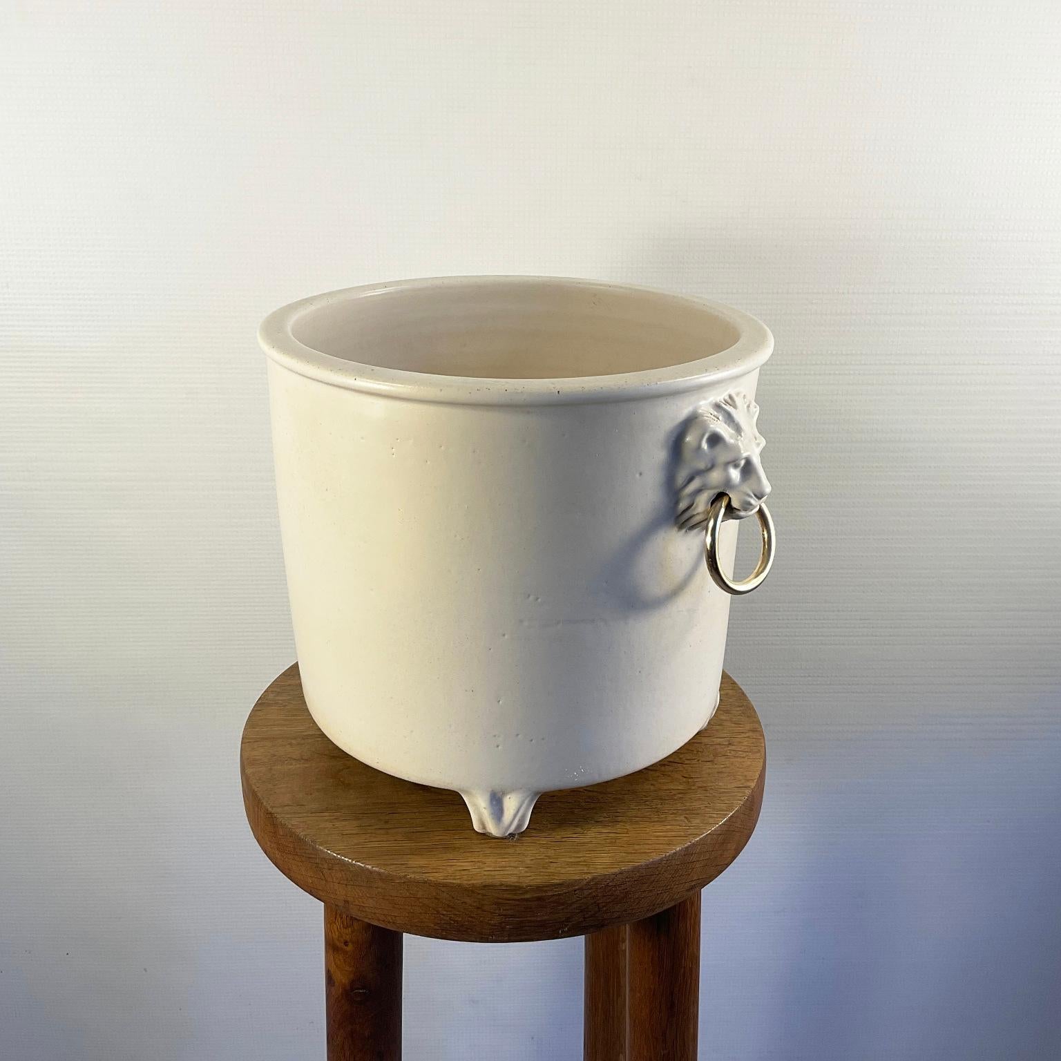1960s cream glazed ceramic footed planter or flowerpot with decorative lion heads on either side holding a brass ring.
Signed engraved 1326.G.M. Poterie Pol Chambost France 
