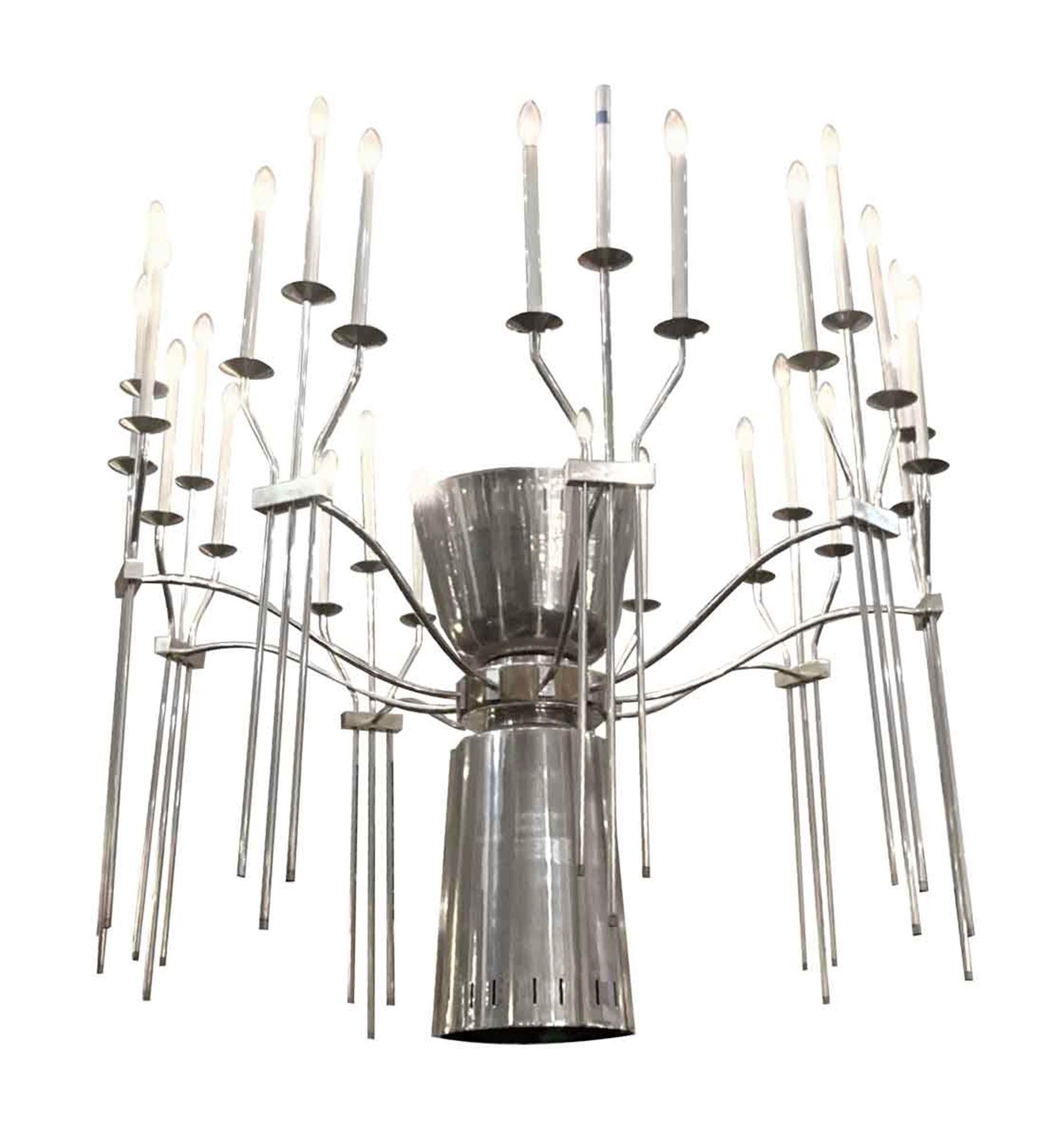 1960s Mid-Century Modern polished aluminum chandelier and brass accents. 27 candlestick lights with four flood lights in the center body - one single light that shines down and three lights that shine upwards. Includes long pole. We have small
