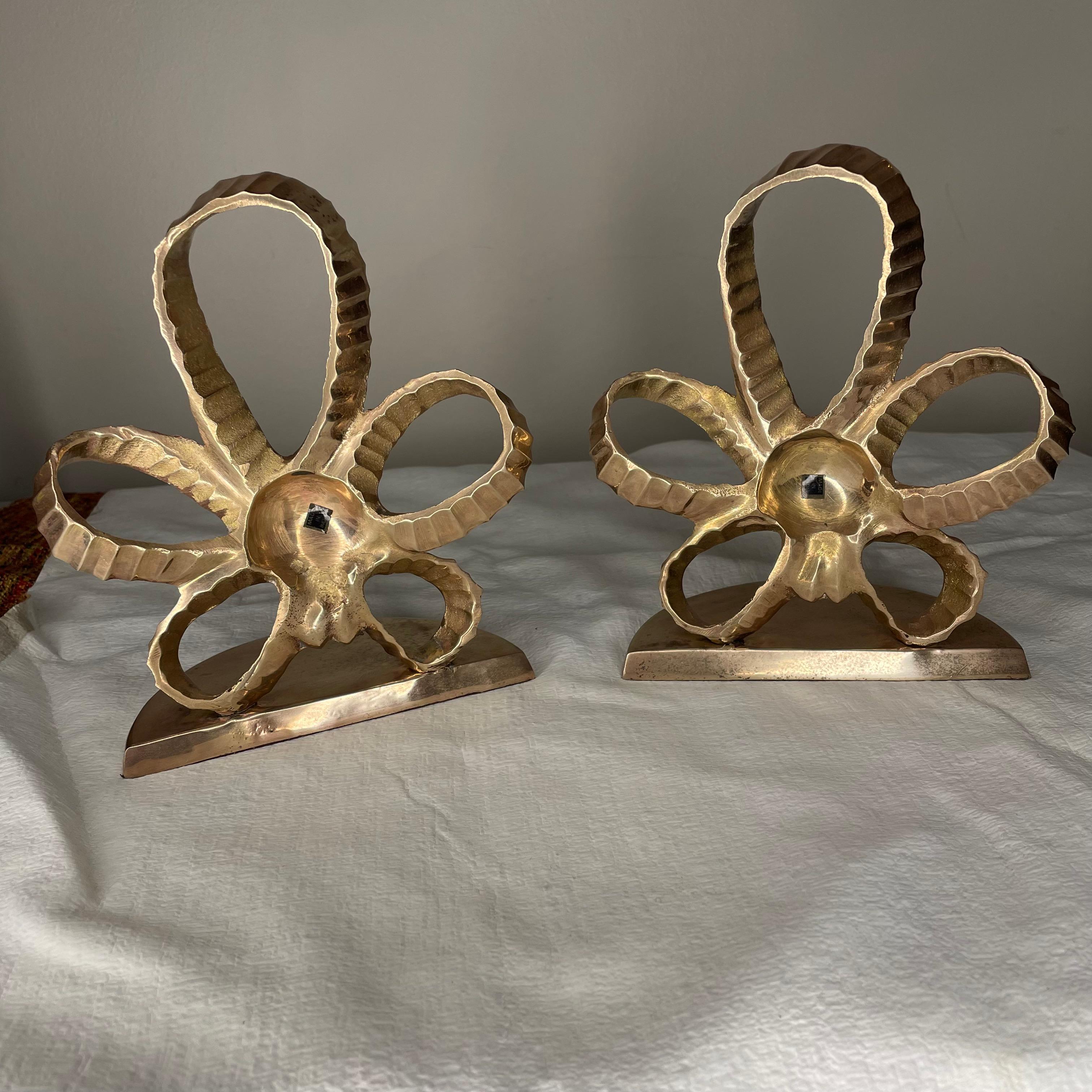 Pair of polished brass bookends with a brass faux ribbon detailing in the shape of a star. Both pieces are made of solid brass which has recently been polished. No lacquer coating on top allowing for patina to set in over time.