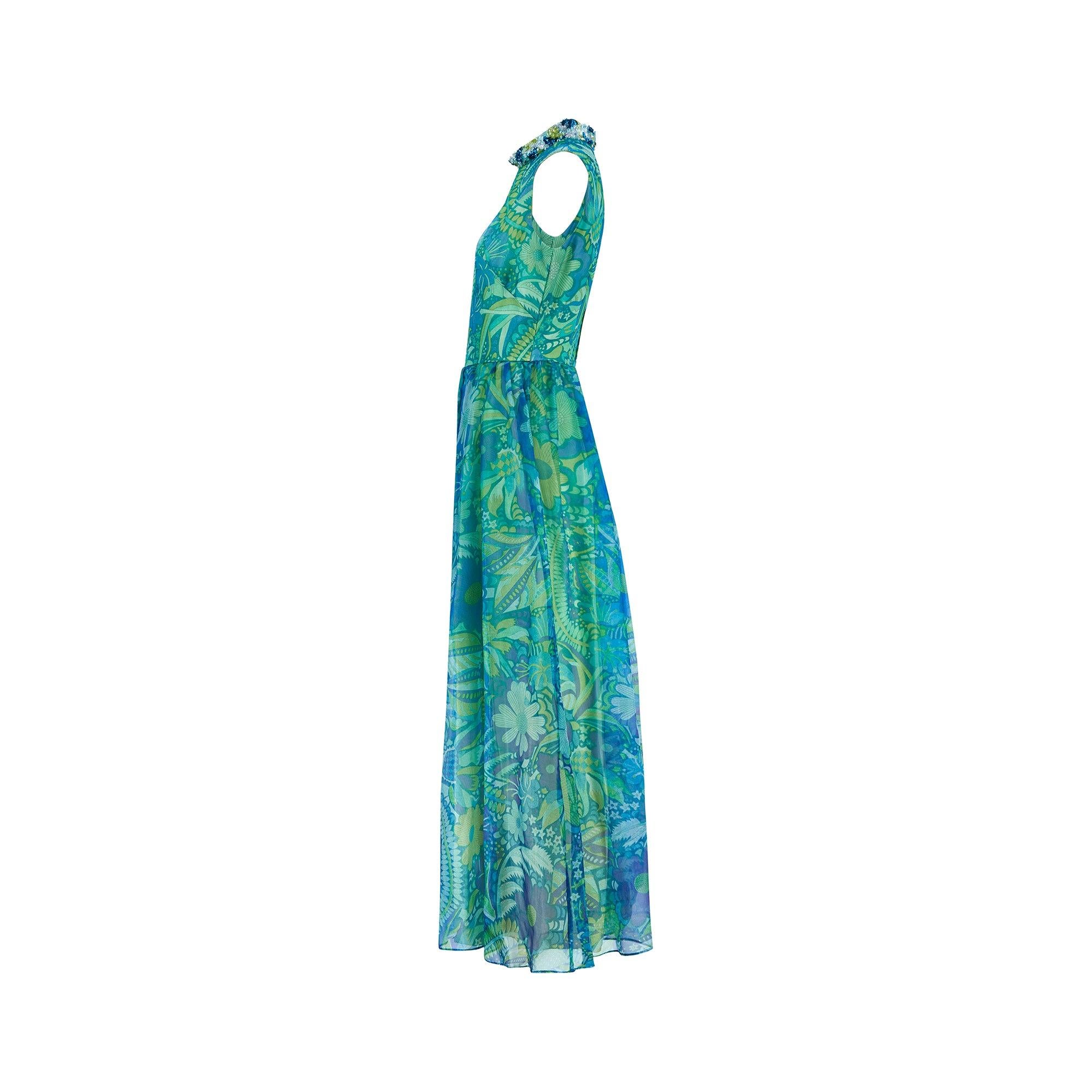 This incredible jumpsuit was created by Polmarks in the 1960s. Tailored from flowing sheer georgette printed with psychedelic florals in bright blue and green hues, this theatrical piece is cut to an extreme wide-leg silhouette. The high collar is