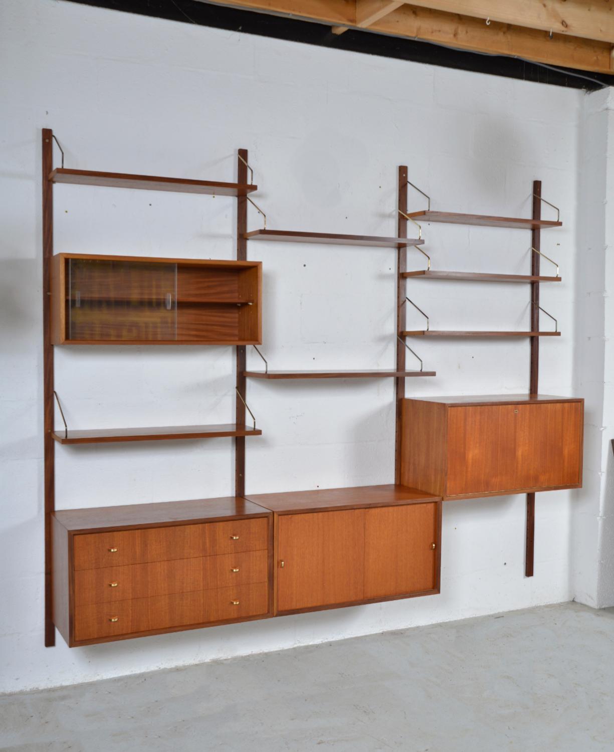 This highly versatile and functional “Royal System” was originally designed by Poul Cadovius in 1948. This particular piece is quintessentially Mid-century Modern being the first generation identified by the demi-lune brass handles. This three-bay