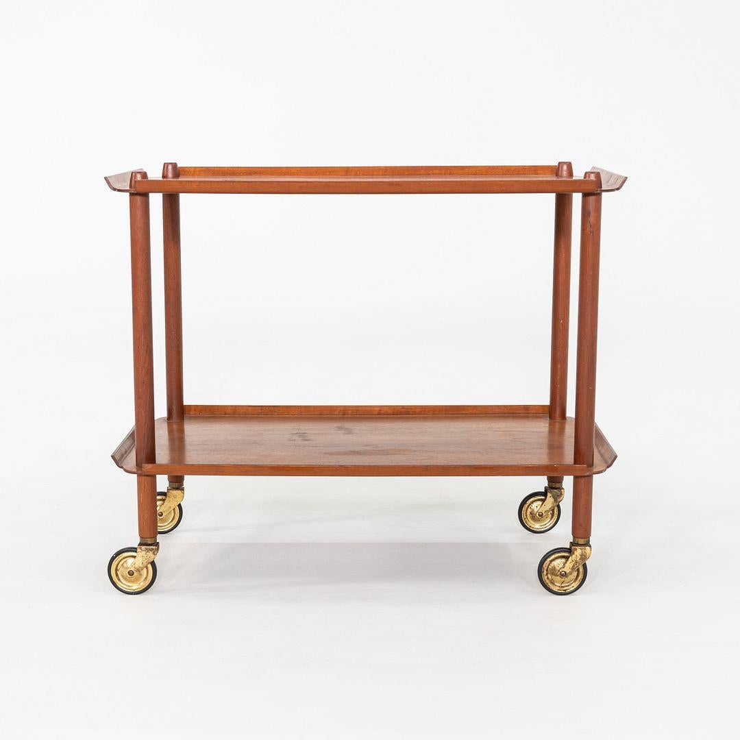 This is a bar cart designed by Poul Hundevad for Vamdrup Stolefabrik. This particular example was produced in Denmark and dates back to the 1960s. Crafted from solid teak with veneered surfaces, the cart features two removable trays with gently