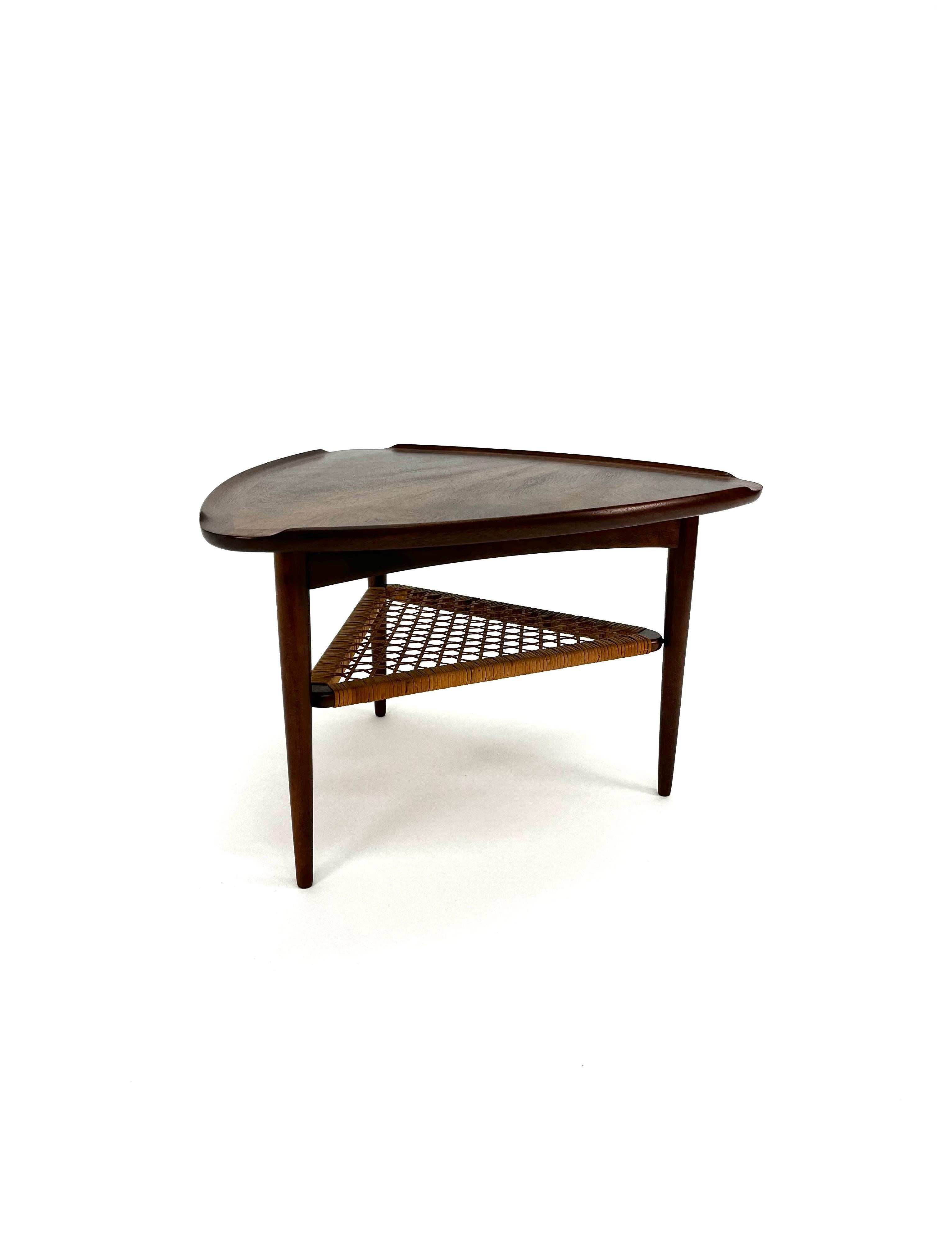 Danish Mid-Century Modern Poul Jensen for Selig Guitar Pick side table in teak woven cane. Featuring a unique raised edge top triangular surface and lower tier magazine shelf made of woven cane. Original stamp 