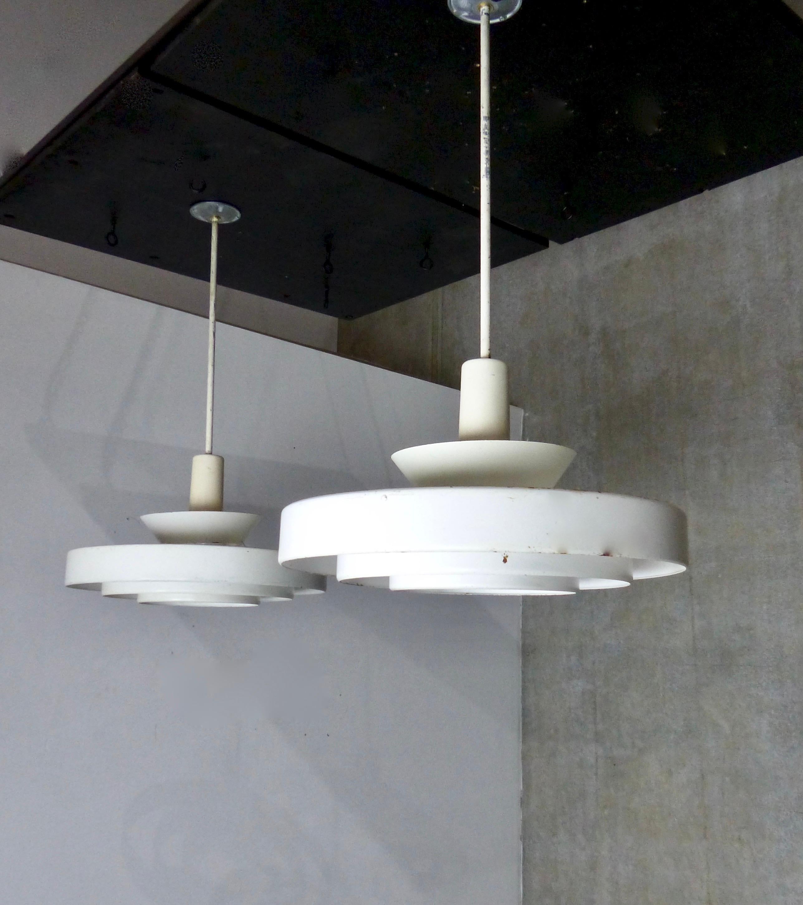 Matched pair of Mid-Century Modern pendant lights by Prescolite. The Minimalist design features three tiers of 'Saturn' style concentric metal rings. Re-wired and CSA approved to current electrical standards; ceiling mounting plate included.