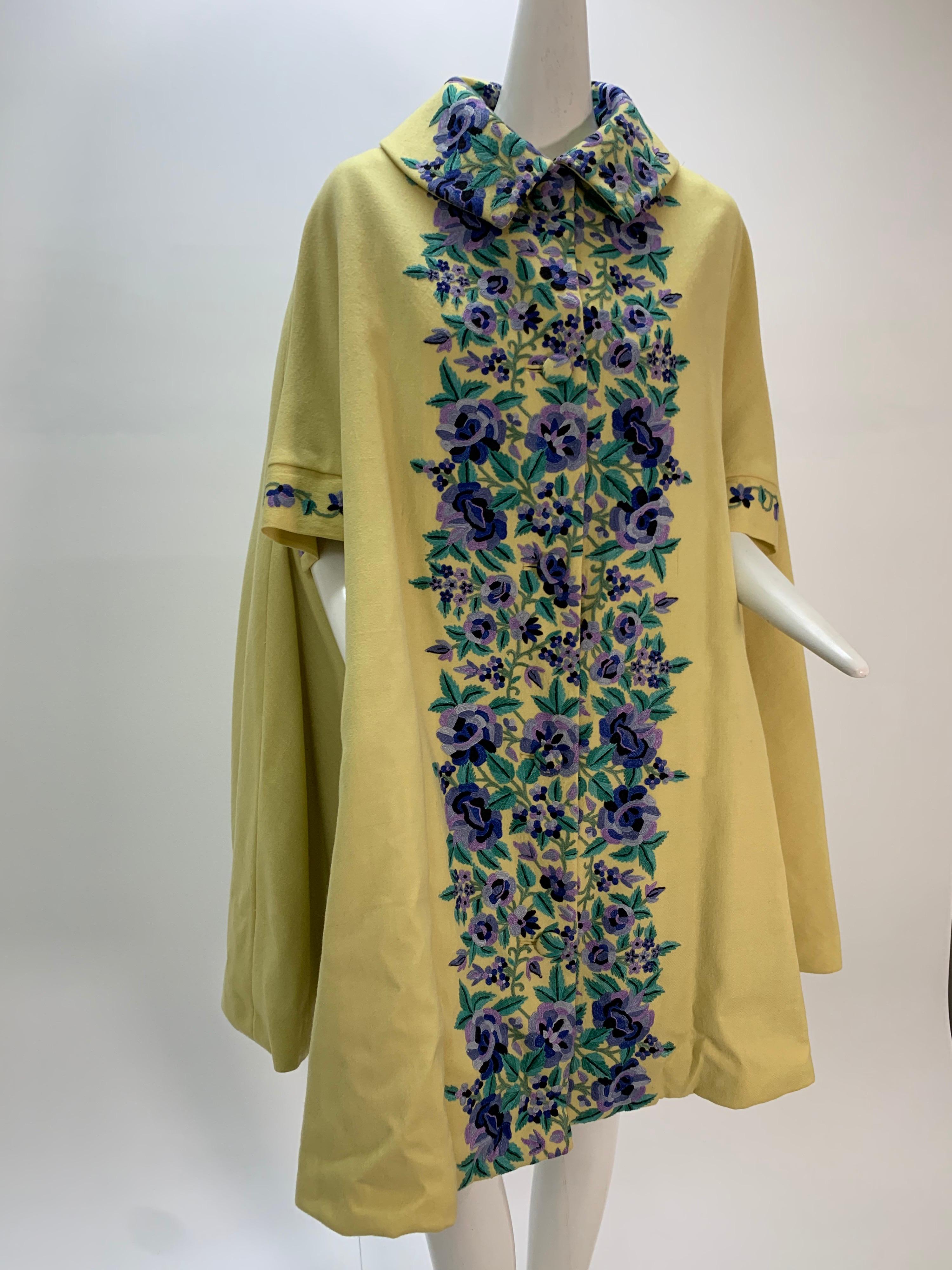 A gorgeous 1960s Profils Du Monde citrine color wool swing coat with beautiful lavender, indigo and green floral crewel embroidered floral panels at front. Lined in blue silk satin with a matching size 10-12 silk dress. 