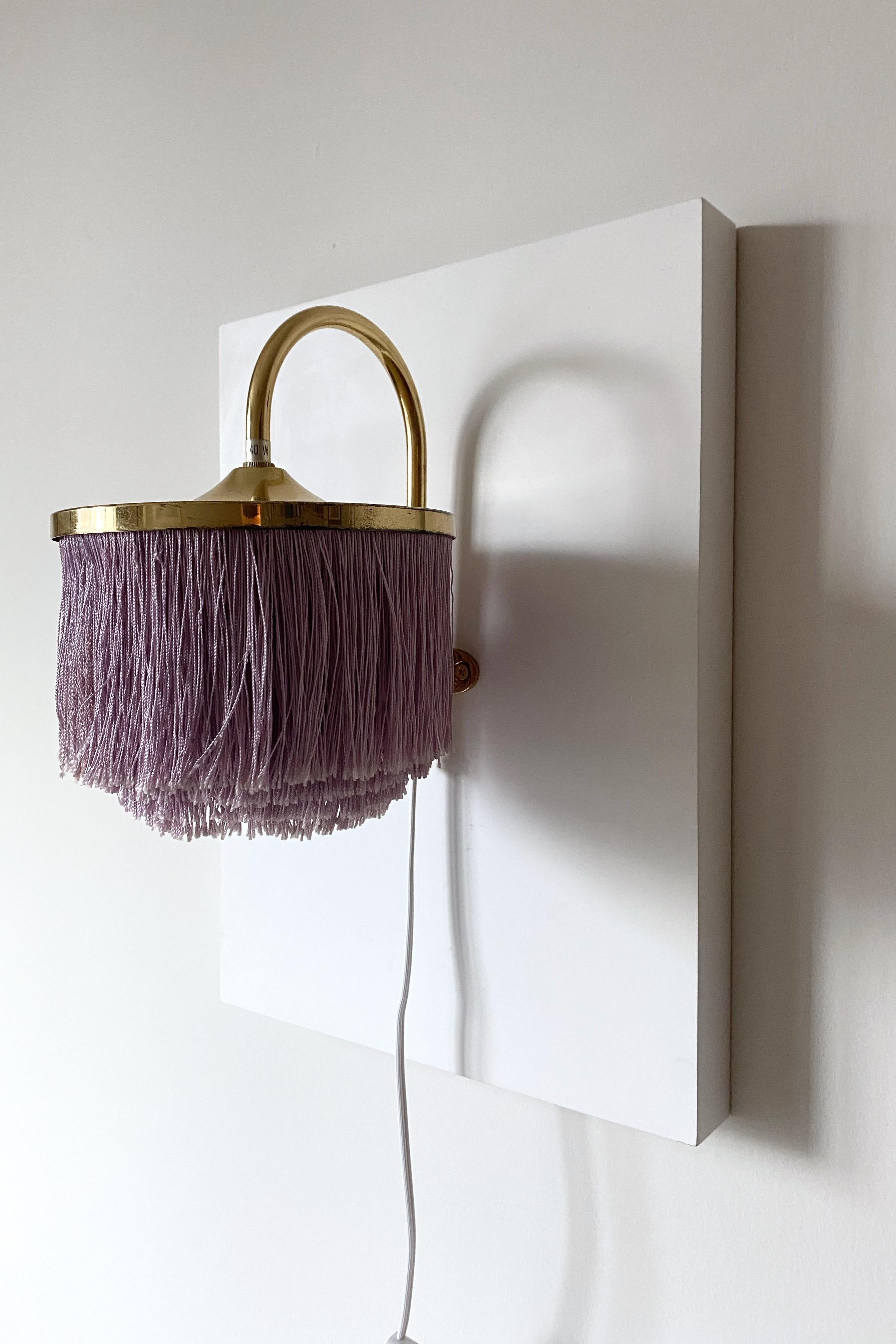 Vintage Wall light modell V271 by Hans-Agne Jakobsson. Part of Hans-Agne Jakobsson now iconic fringe lamp collection this piece has light purple colored silk fringes and brass lamp arm. It is a super charming wall light that will bright up any