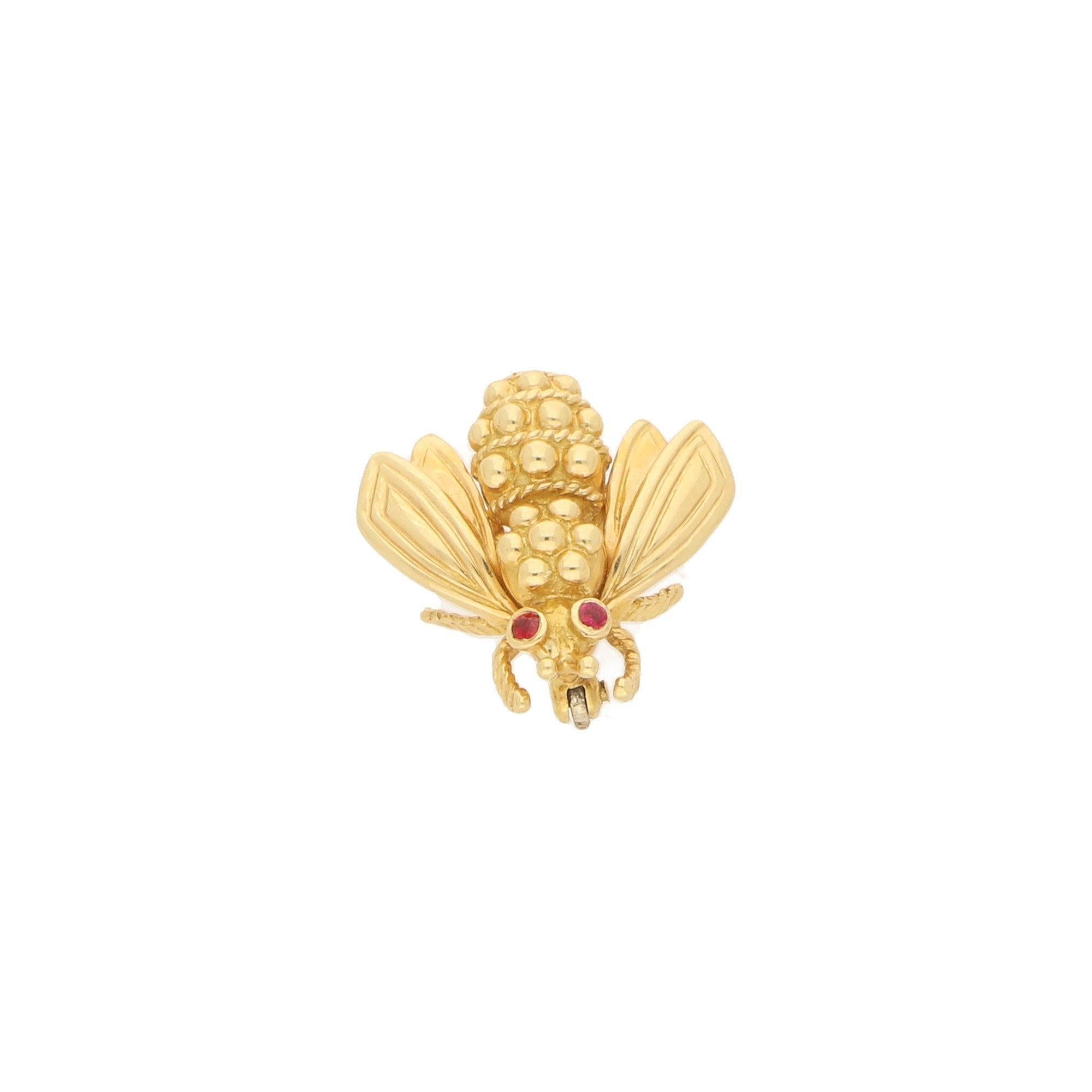 A vintage Tiffany & Co. ruby-eyed queen bee brooch in 18-karat yellow gold, circa 1960. The brooch is designed as a stylized queen bee in yellow gold with the body composed of gold beads within ropework detailing.
The textured head is accented with