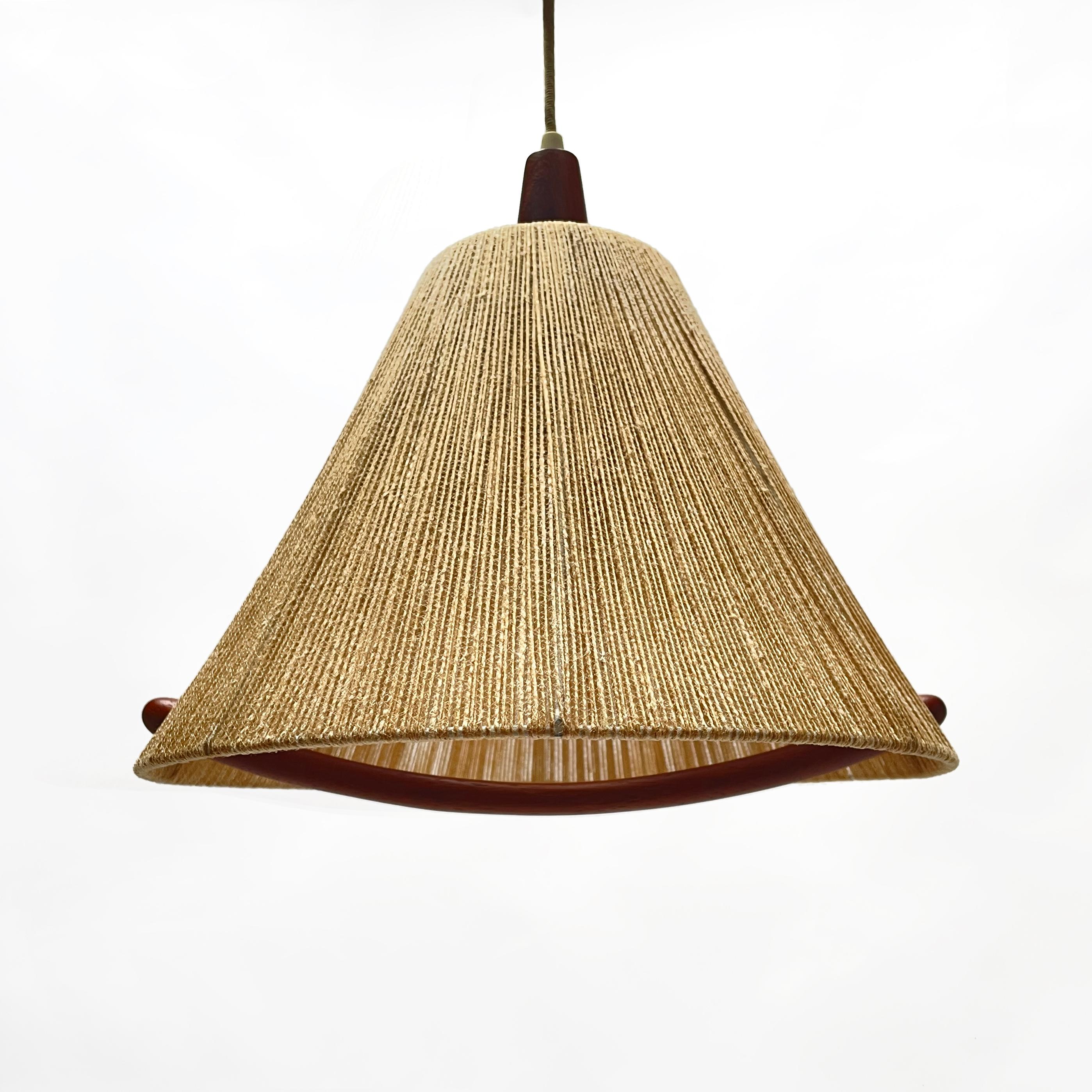 Charming Temde teak and raffia hanging lamp from the 1960s. 
The lampshade itself is made of raffia and has beautiful teak details. With the help of the teak handle, the lamp can be easily adjusted in height. The pull mechanism in the teak canopy