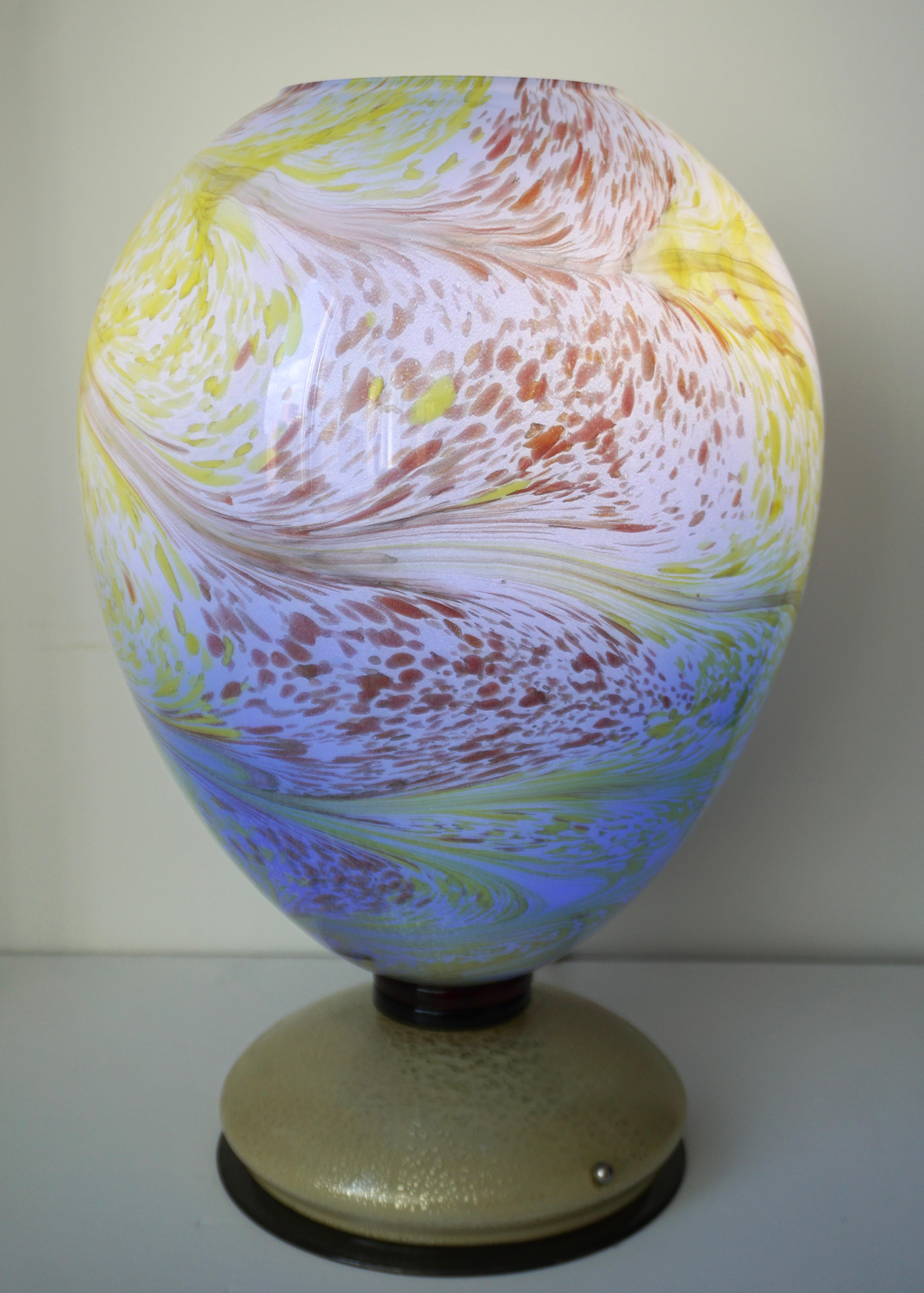 Italian Venetian egg-shaped lamp in mouth-blown Murano glass worked with fantastic swirls of colors and overlaid so that the colors change depending on the light, on a cream glass base worked with expanded pure gold leaf, resting on a metal plate.