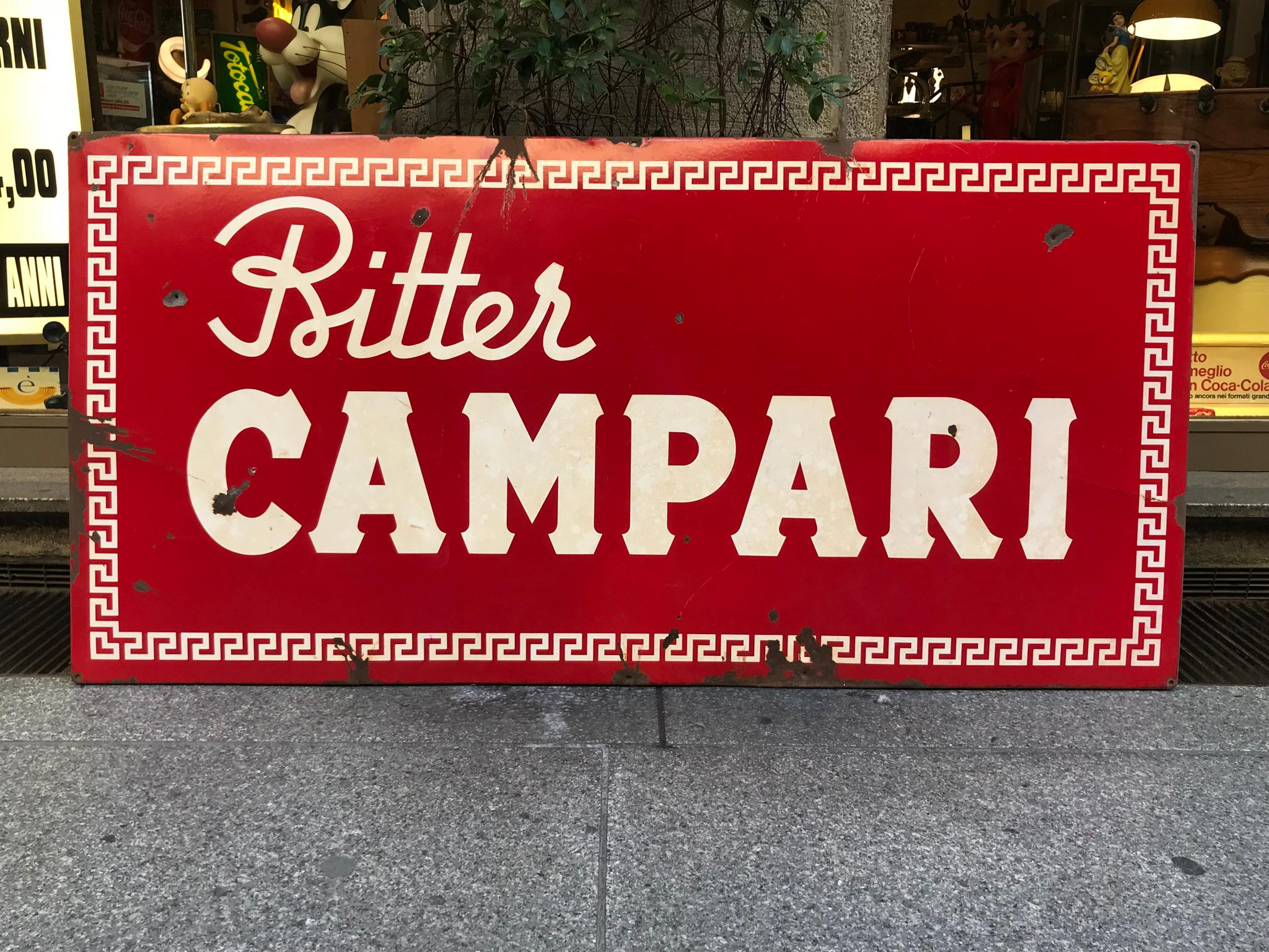 Dieses große und auffällige Emaille-Metallschild von Bitter Campari wurde in den 1960er Jahren in Italien hergestellt.

Es gibt kleinere Verluste von rotem und weißem Email.

Das Schild wurde in den späten 1970er Jahren mit einem Holzrahmen