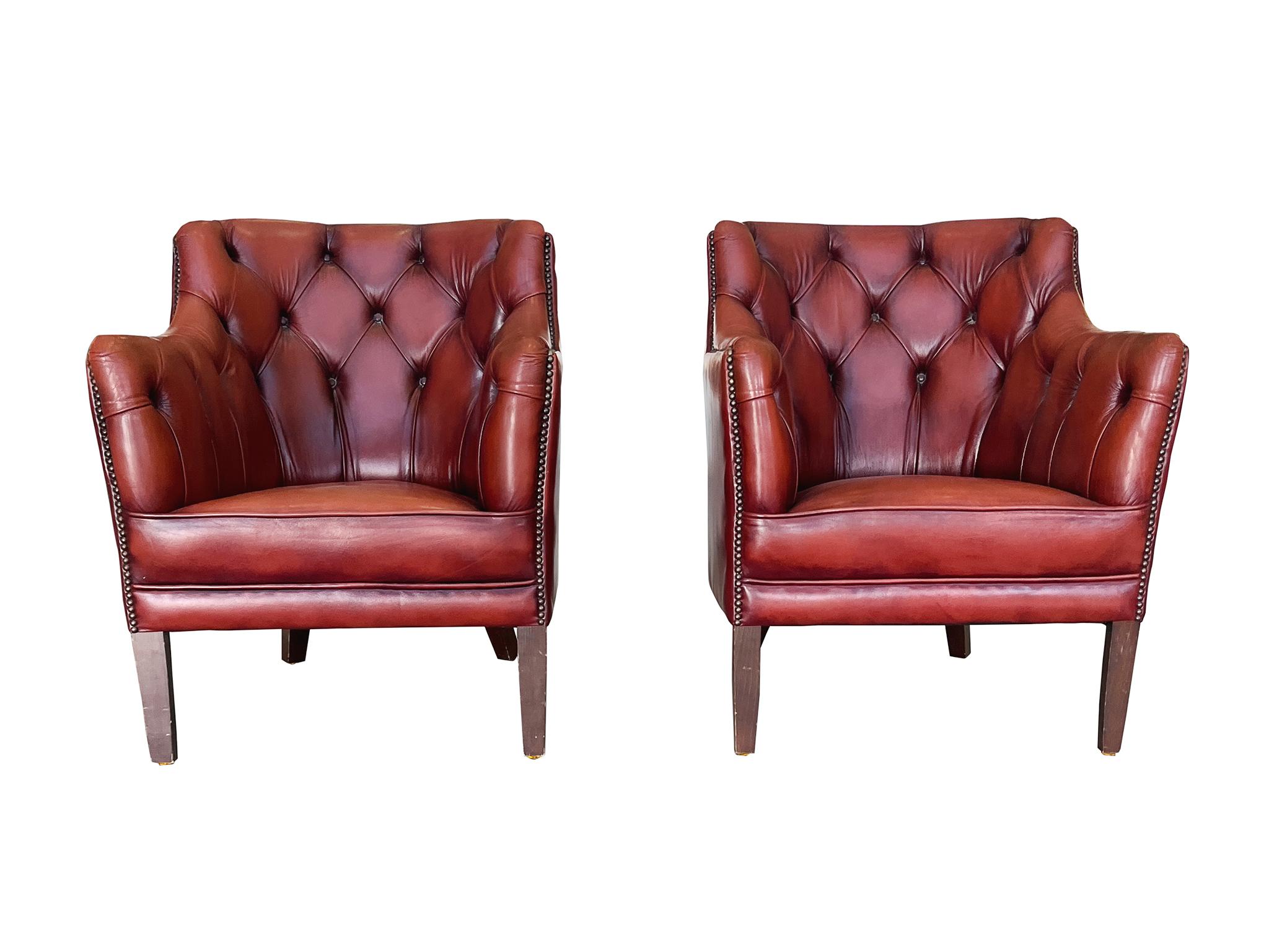 Made in the 1960s, these Danish barrel armchairs have beautifully aged leather upholstery in a pomegranate red. The interior back and arms are tufted in a Chesterfield style, while the trims are lined with brass studs. Other features include the