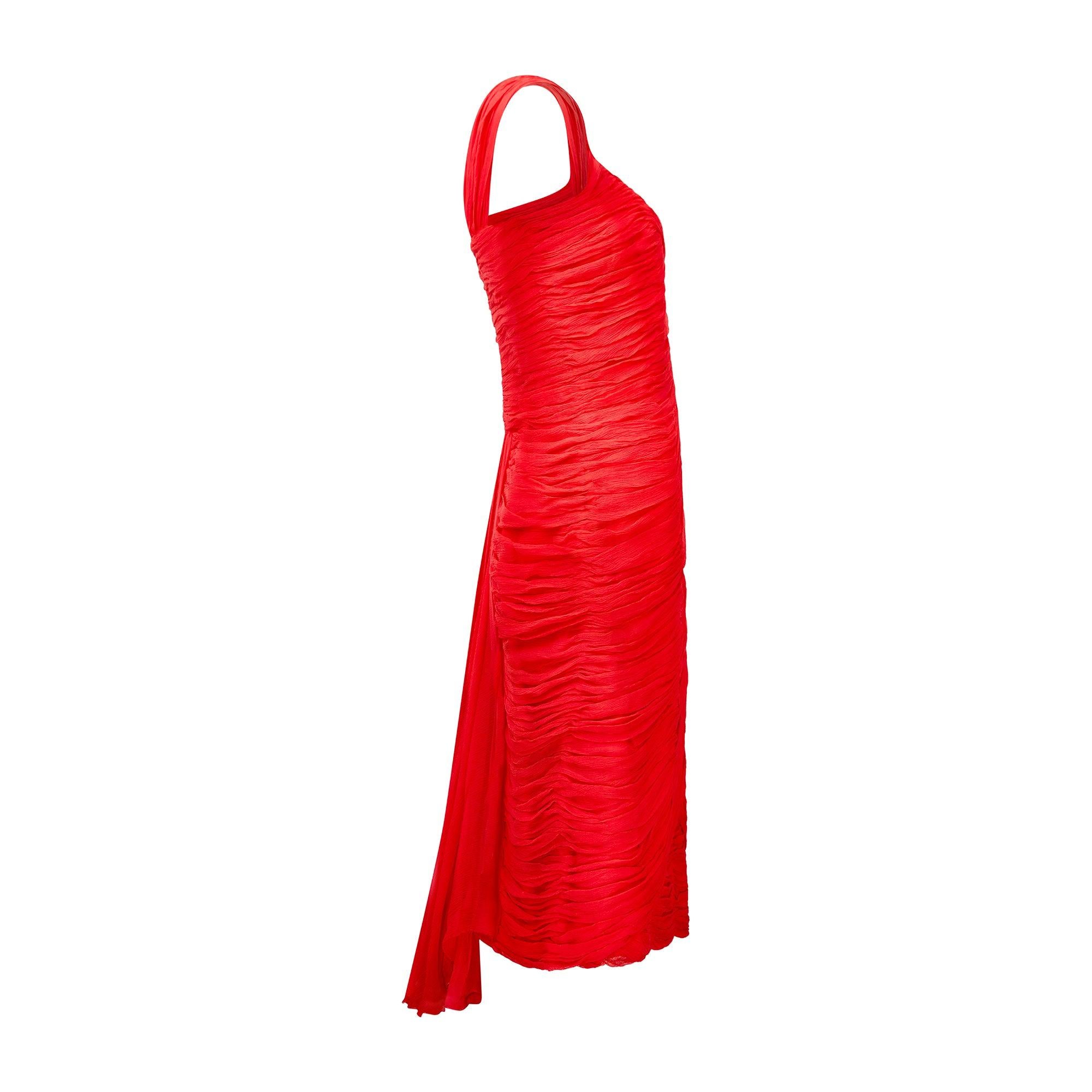 This lively, crimson party dress was designed in the early 1960s or possibly even late 1950s and echoes the famous draping of the French couturier, Jean Desses. It has been delicately crafted from swathes of pleated, pillar-box red silk chiffon