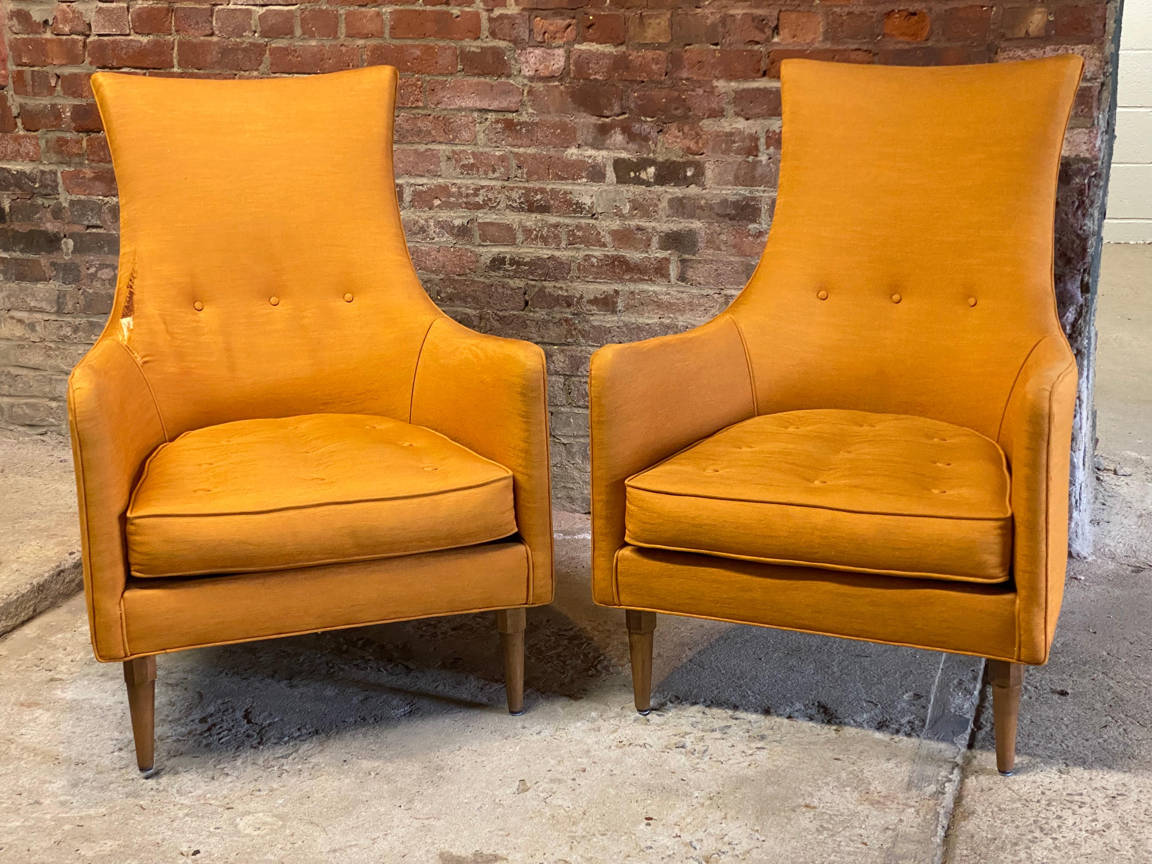 A very nice pair of 1960s upholstered high back chairs. Featuring sculpted and arched backs and arms, buttoned backs and seat cushions and solid wood legs with faceted tops. Fun and fresh orange fabric upholstery.

One chair is in good condition
