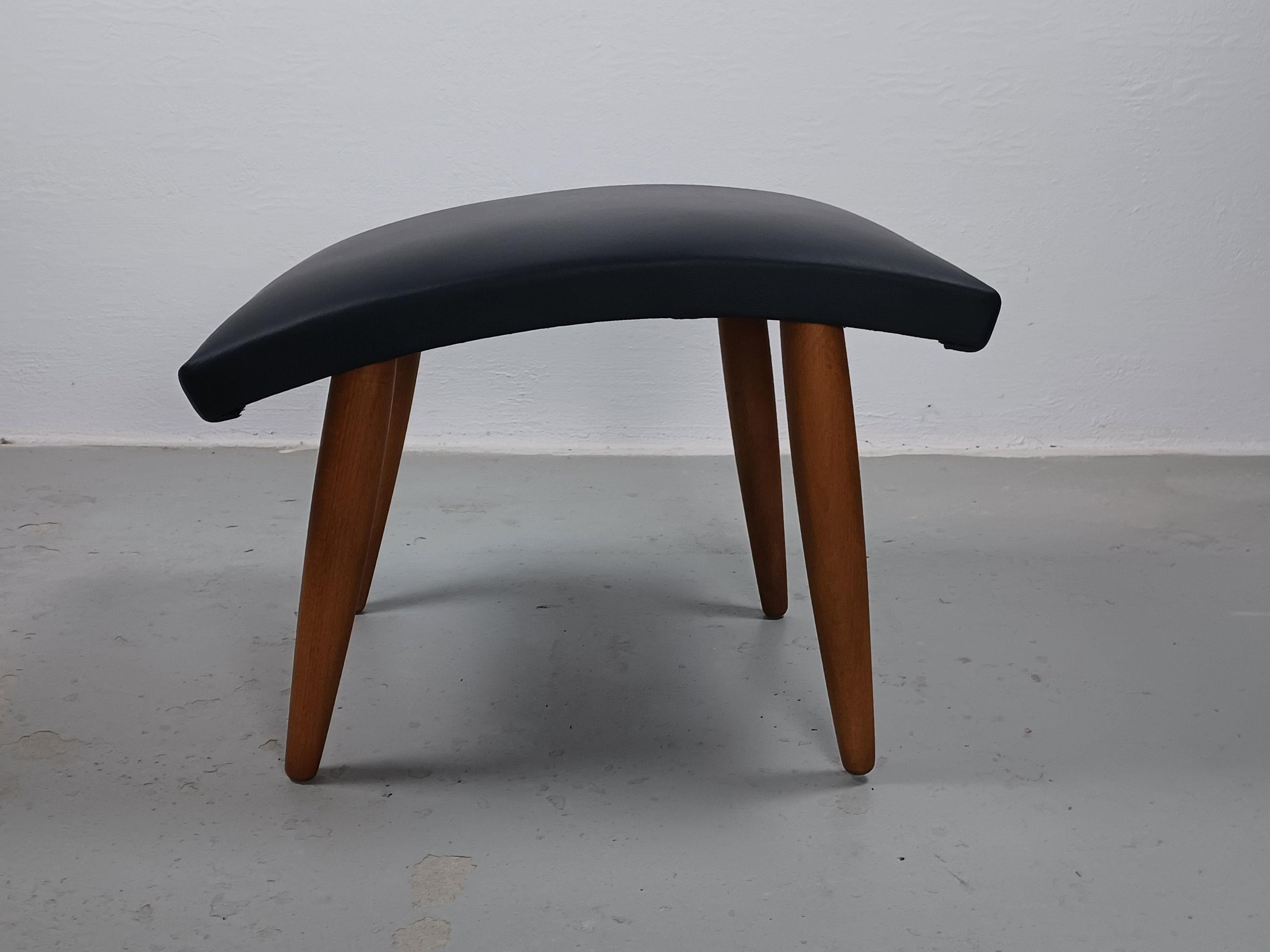 1960's Restored Danish footstool reupholstered in black leather.

Fully restored Danish footstool in slimlined minimalistic yet advanced Scandinavian modern design with it's combination of straight simple lines combined with it's organic curved