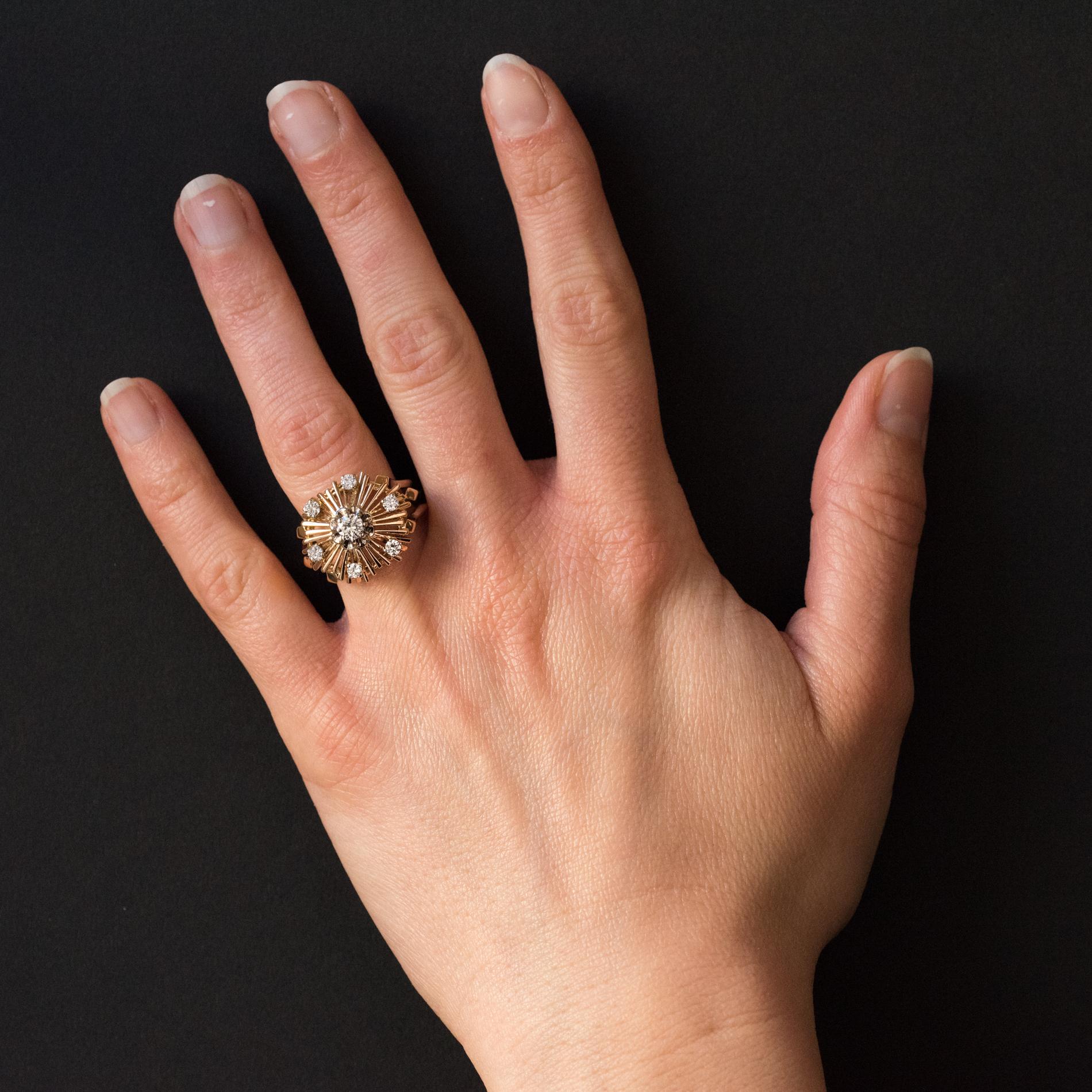 Ring in 18 karat rose gold.
Retro ring, the mounted is made of gold threads arranged to form a radiant decoration and set with a brilliant- cut main diamond surrounded by 6 other diamonds. The beginning of the ring is made up of 3 gold threads which