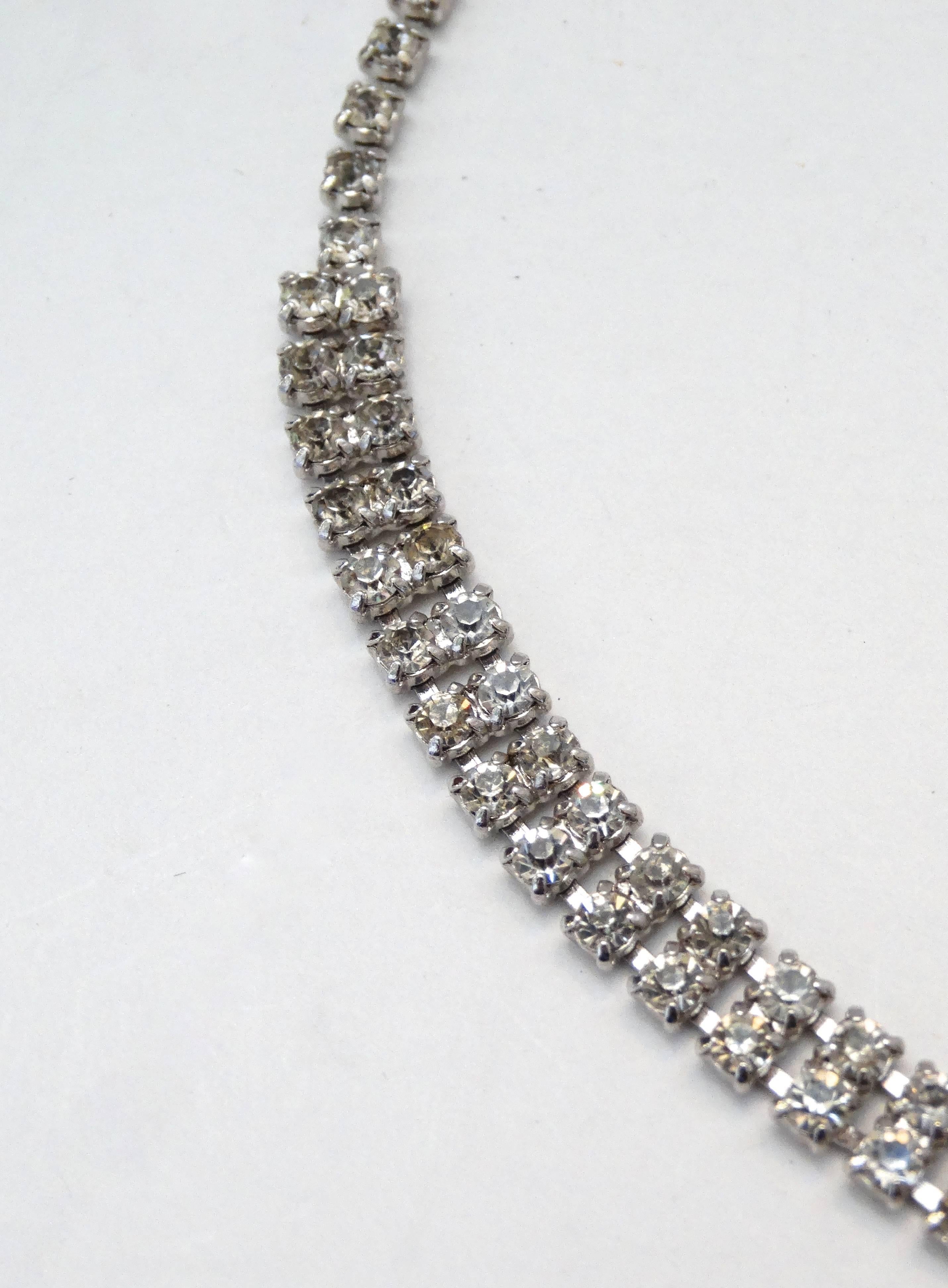 Channel the glamour of the 1960s with this adorable rhinestone pendant necklace! Made of beautifully cut rhinestone gems in various shapes and sizes backed with a quality silver metal. Large bow-like pendant sits at the center. Wears close to the