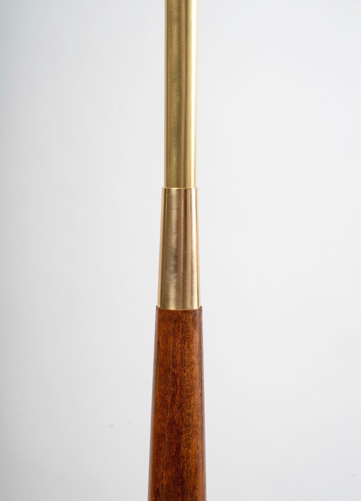 The central shank is adorned with an oblong mahogany shaft underlined with gilded brass on the upper and lower part of the shank.
The whole rests on a tripod (3 feet) in gilded brass.
The floor lamp is dressed in a cylindrical shade in ecru