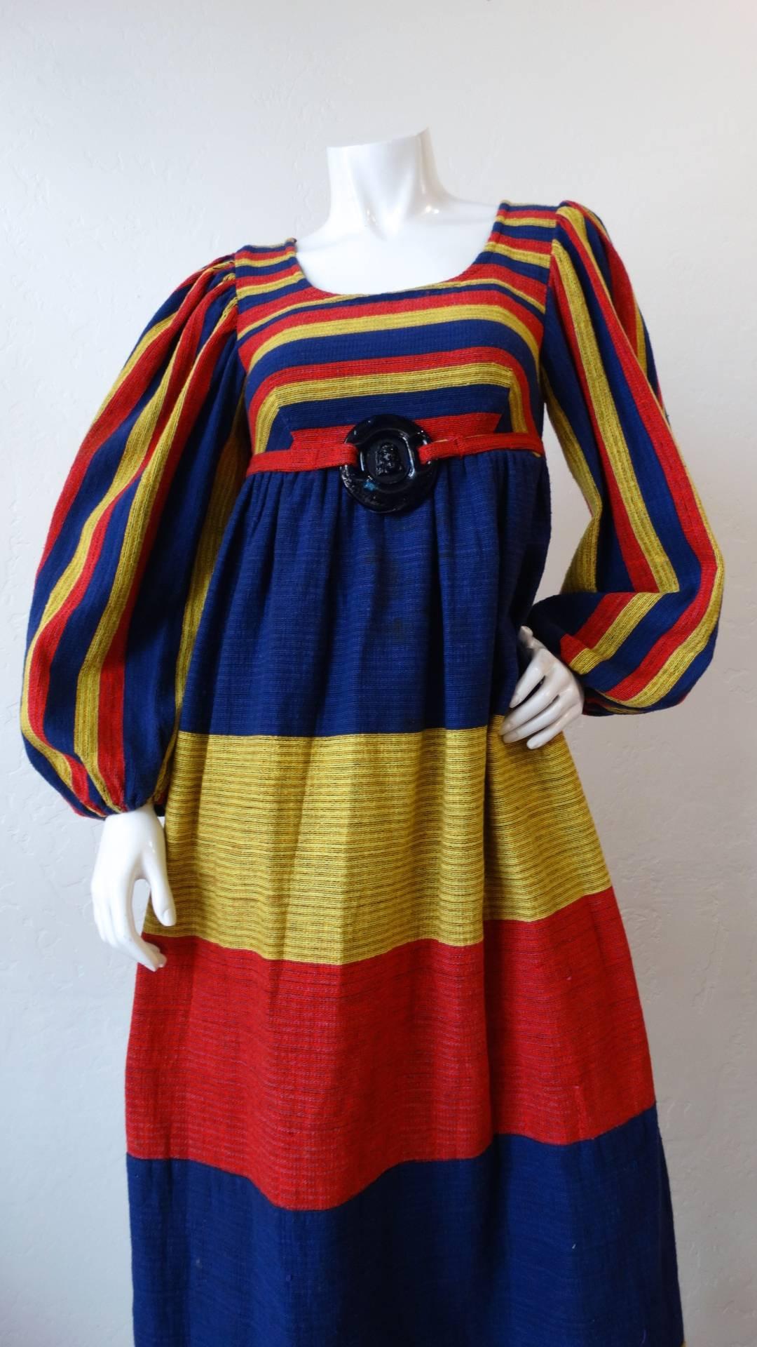 The most incredible 1960s peasant dress from our favorite Israeli vintage designer Rikma! Made of an intricately woven cotton fabric in three shades of red, yellow and blue. Accented at the center of the bodice with a blue medallion, held in place