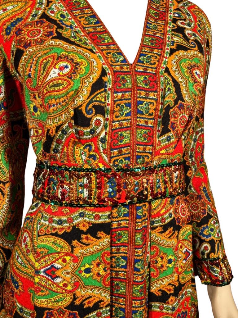 Beautiful bold kaleidoscopic paisley long sleeve, mid-length dress with bright orange, yellow, green and blue over black. Pleating detail in the front and back. Sequin belt and matching cuffs. Designed by Roger Milot for Fred Perlberg. Fred Perlberg