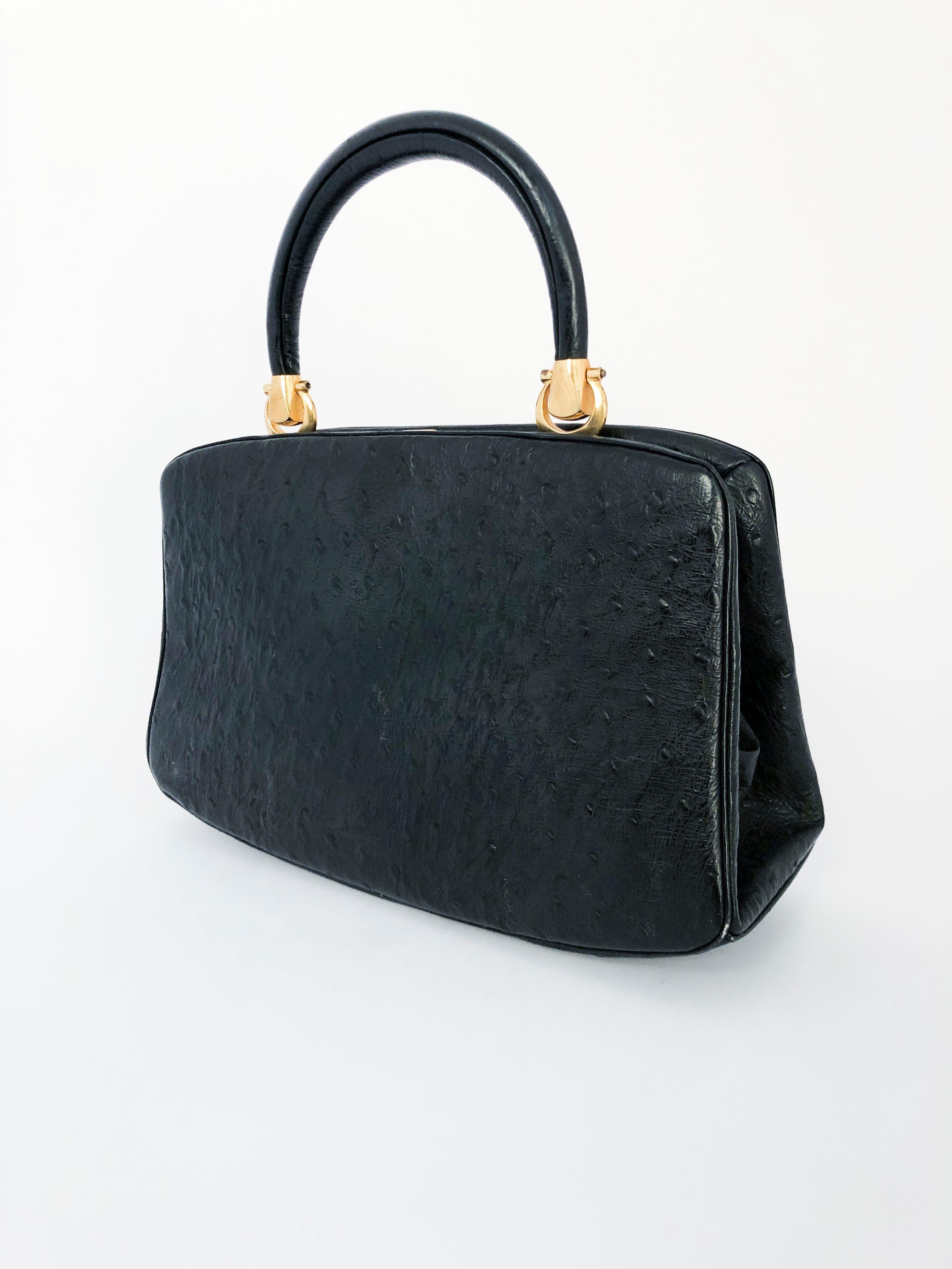 1960s black embossed leather with ostrich texture, articulating handle, and solid brass hardware.