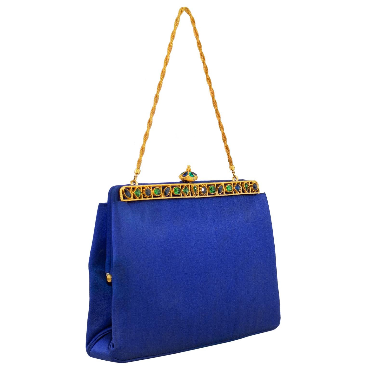 Brighten up any black evening or cocktail dress with this 1960's Rosenfeld royal blue satin evening convertible clutch. Gold tone hard case clasp embedded with faux emeralds and sapphires. Rope style short chain handle which tucks away perfectly on