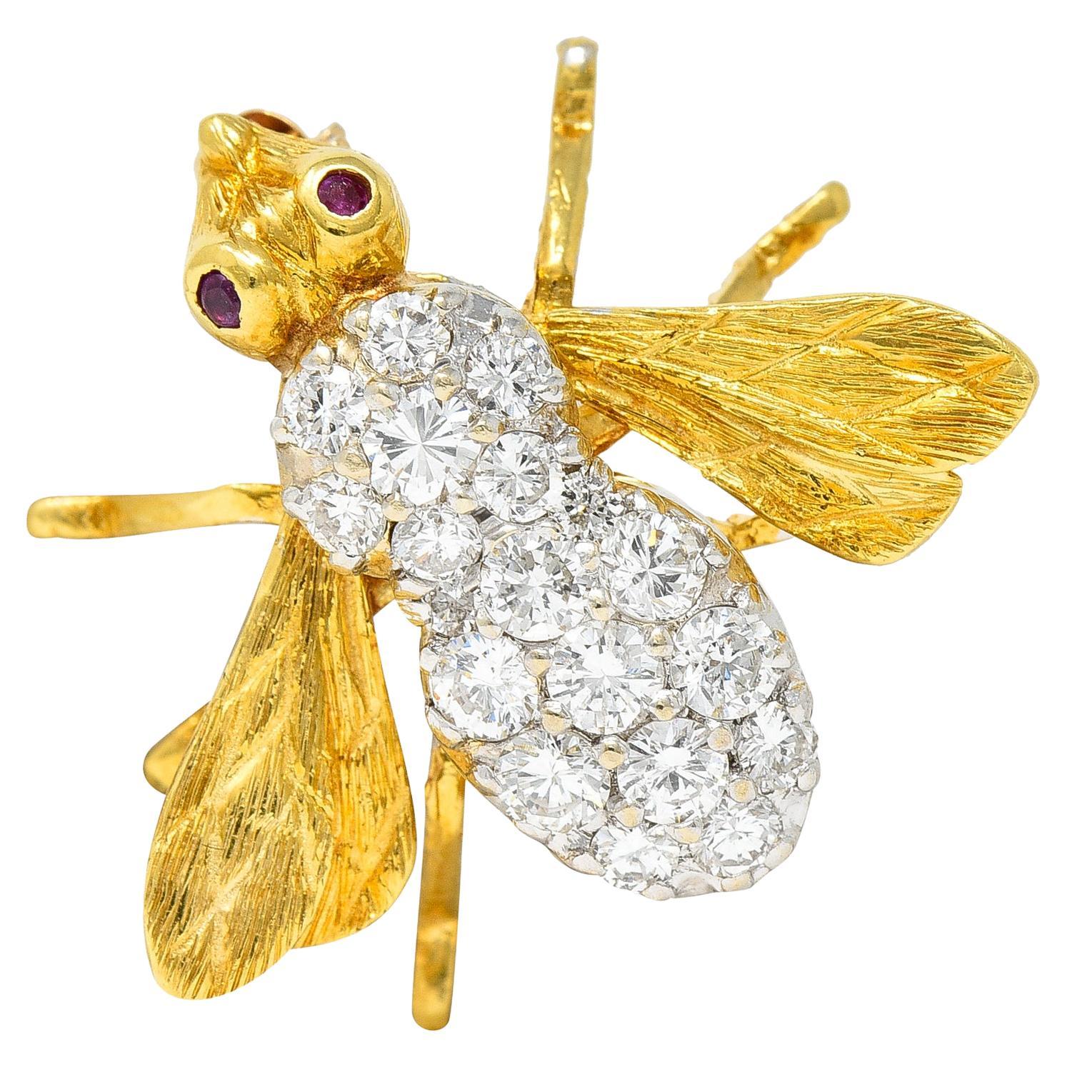 Brooch is designed as a stylized bee with spread and deeply engraved wings. With bezel set round cut rubies as eyes - purple red in color. Weighing in total approximately 0.03 carat. Body is set throughout by round brilliant cut diamonds. Weighing