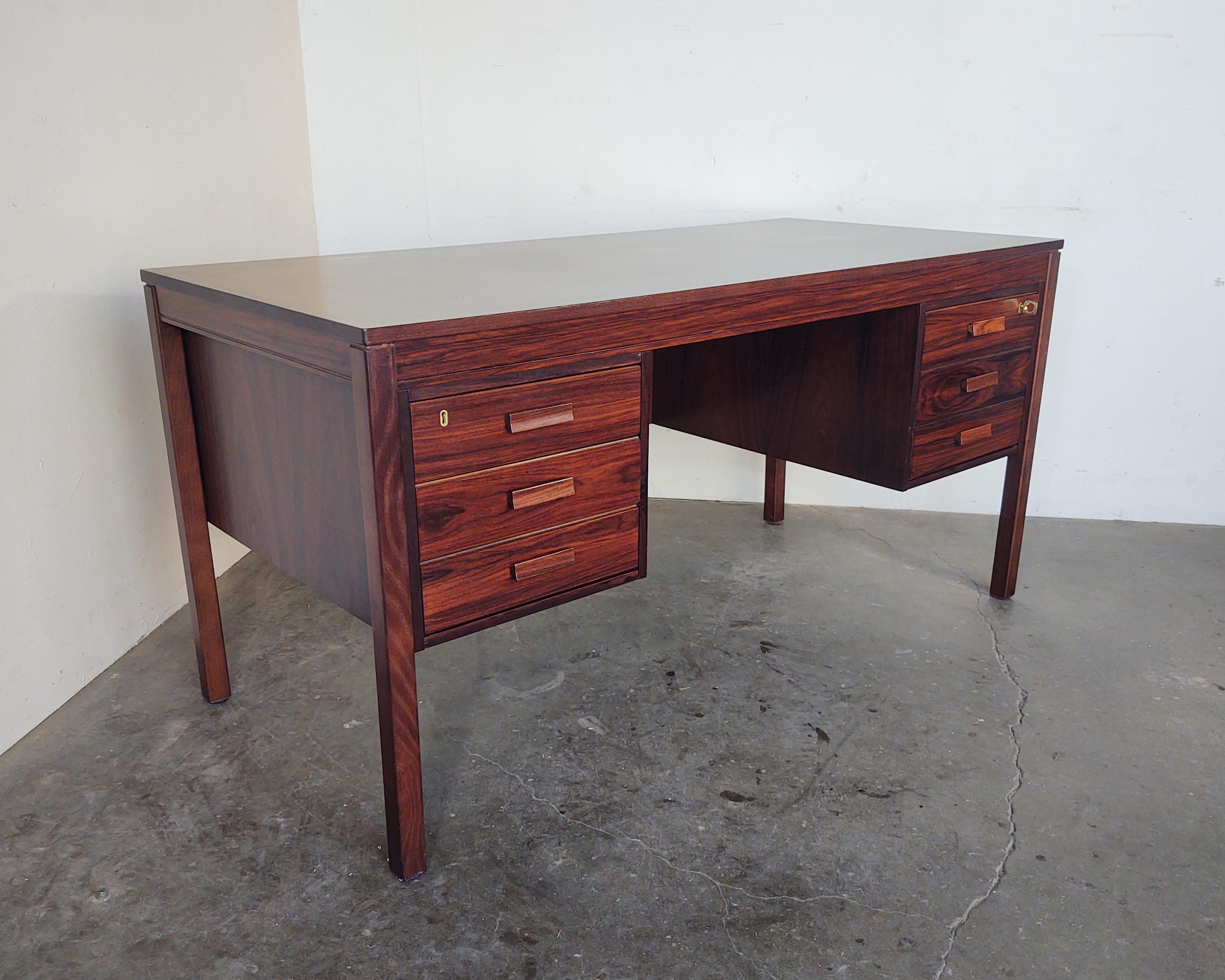 Rosewood desk by Heggen of Norway circa late 1960s. Beautiful wood grain with checkerboard marquetry top. Four drawers, including one large filing drawer on right side and original key included. Overall excellent vintage condition, some very light