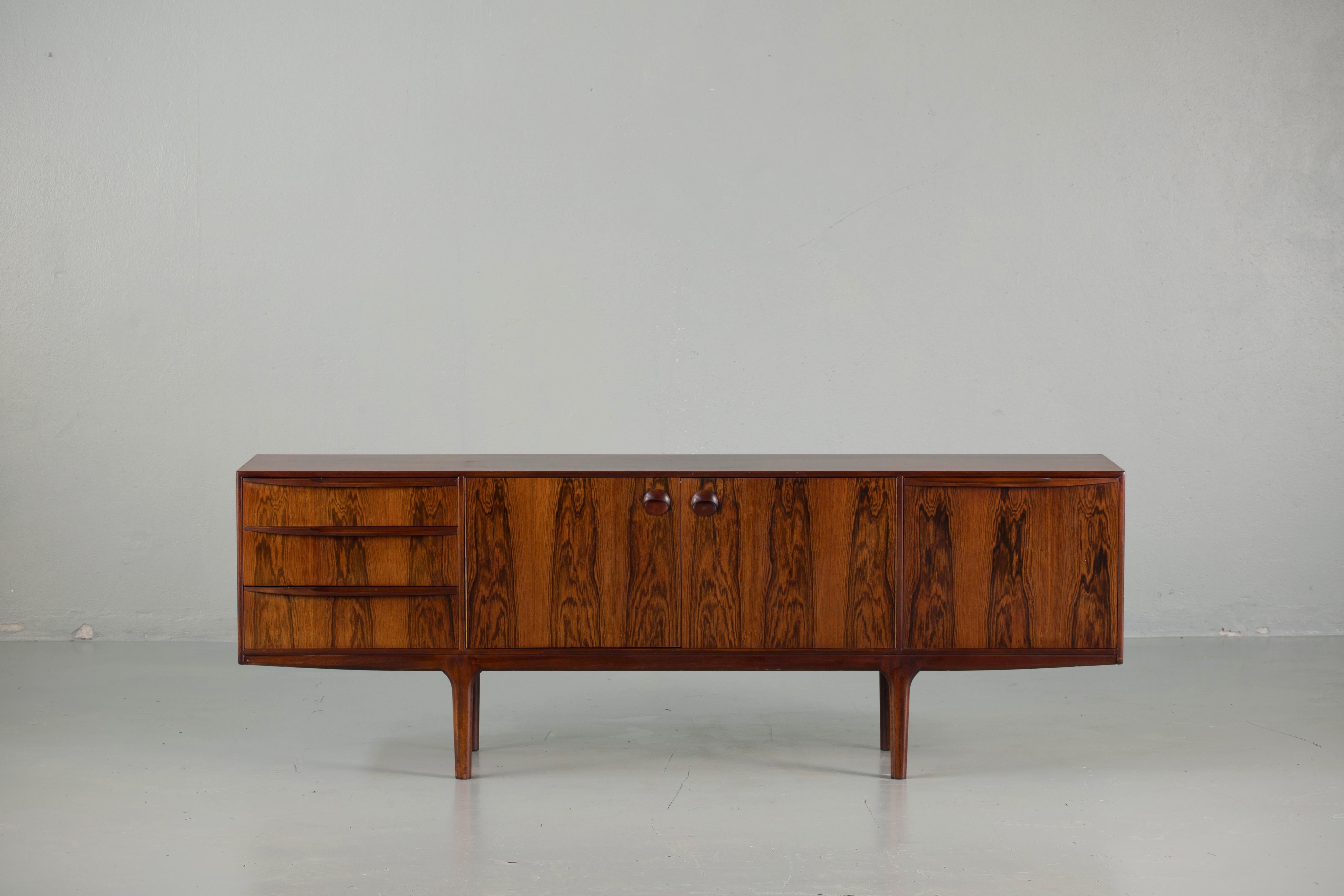 This beautiful vintage modern rosewood sideboard features plenty of room for storage within its three drawers and two large storage compartments hidden by cabinet doors. Sleek two-tone design with unique carved pulls and tapered legs adding to the