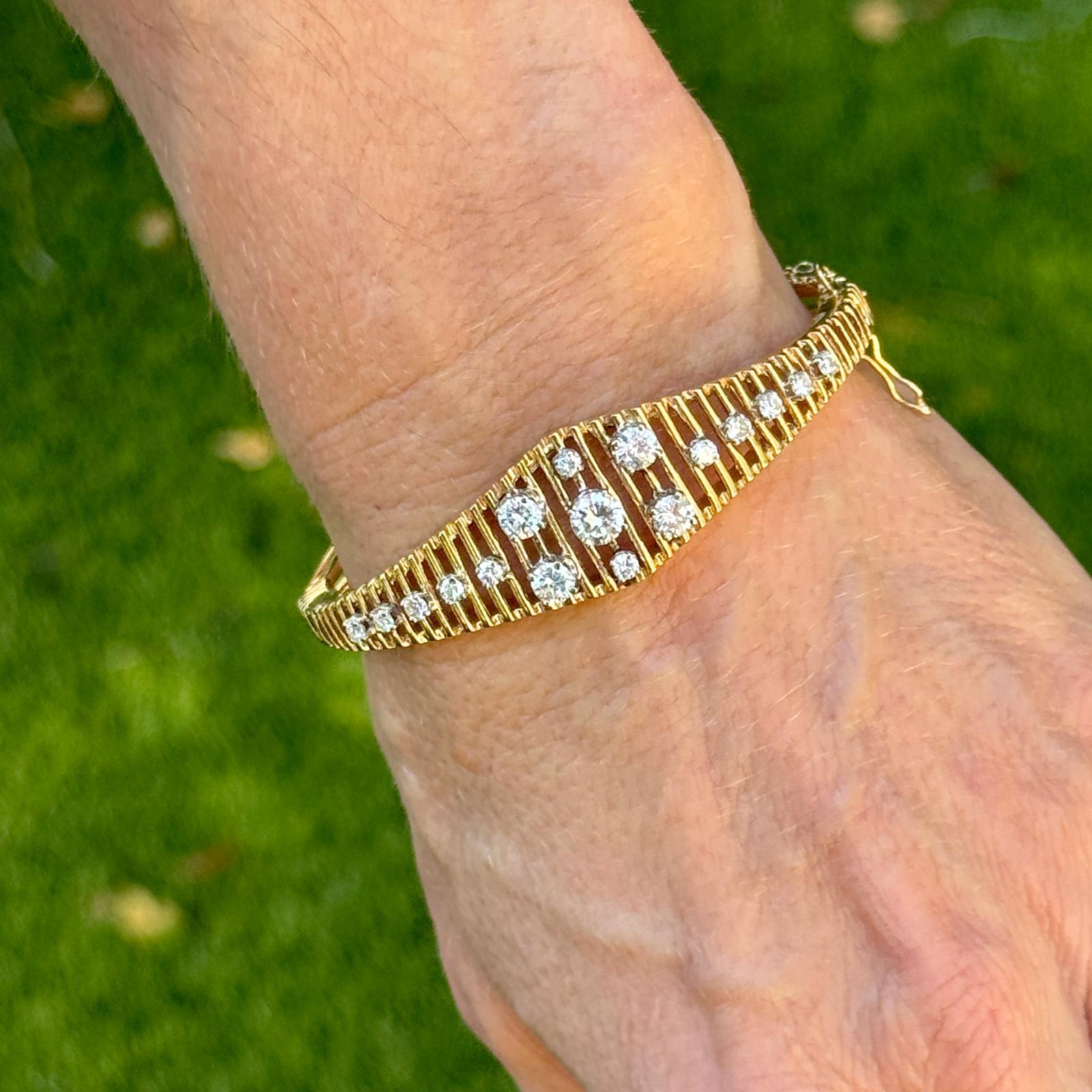 The vintage bangle bracelet is a stunning example of classic elegance and craftsmanship. The bracelet is fashioned in 14 karat yellow gold and features a unique graduated open design that beautifully showcases a collection of 17 round brilliant cut