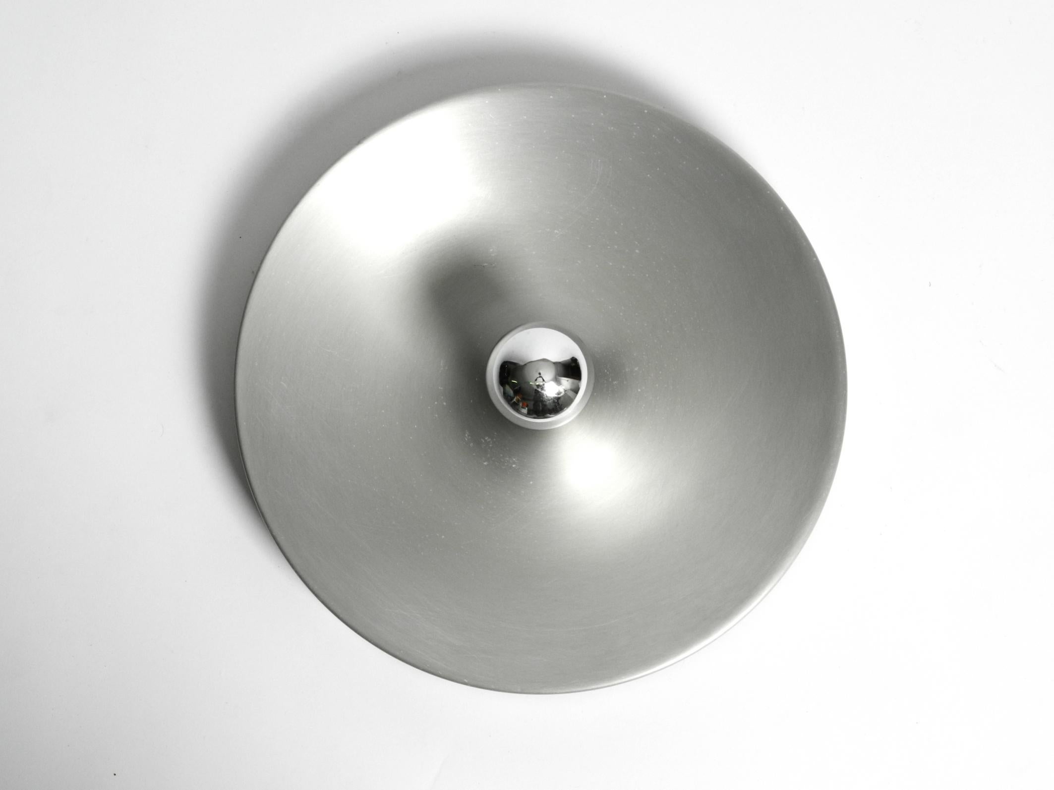 Minimalist large 1960s Space Age Pop Art ceiling or wall lamp made of matte brushed aluminum. Fully functional with one E27 original metal socket. Appearance changes depending on the size or style of the bulbs. Very nice with a mirrored bulb.
No
