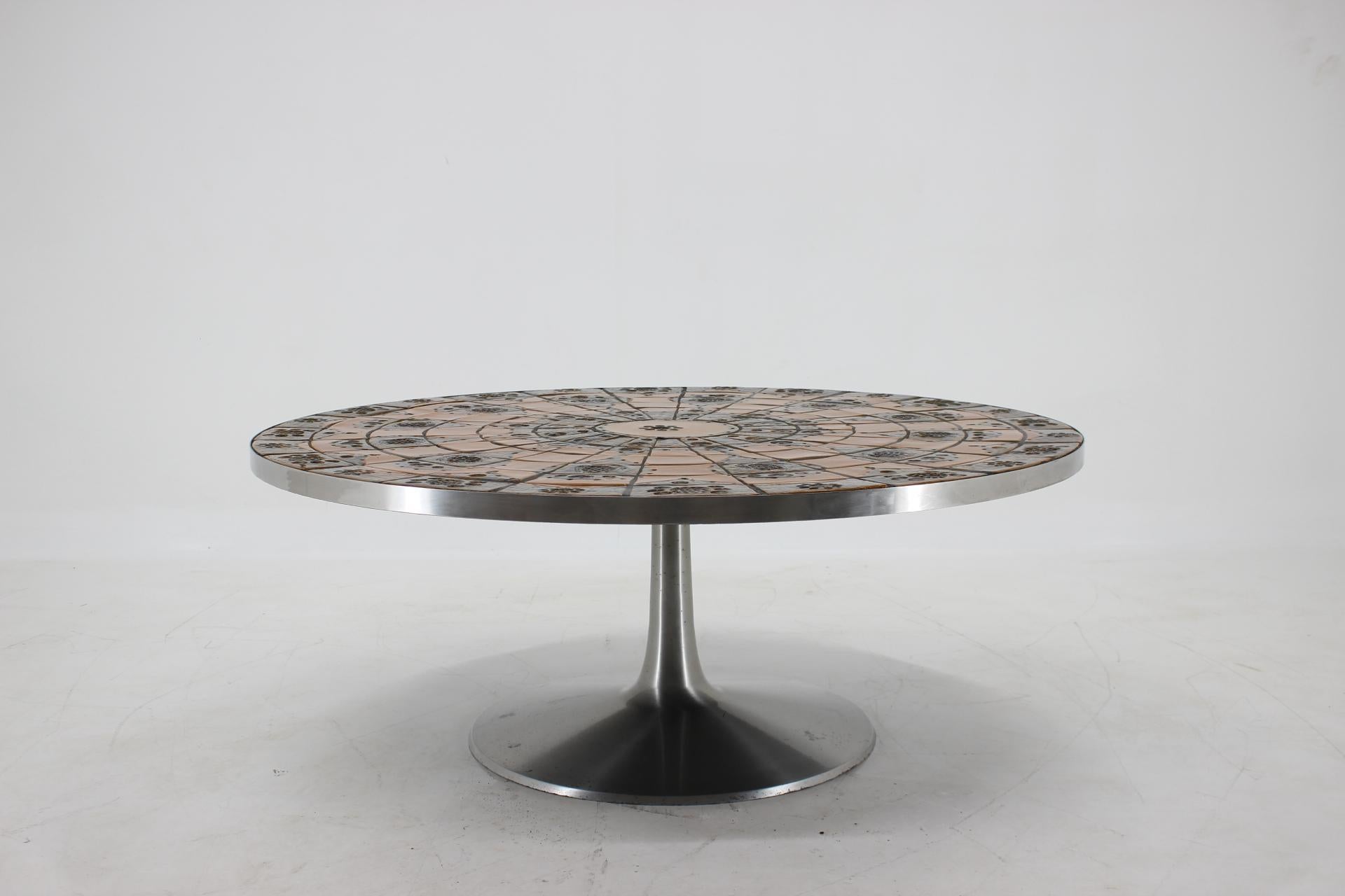 This striking Poul Cadovius coffee table has a stunning tile top by Lilly Just Lichtenberg in burnt orange and earth tones supported by an aluminum tulip style base. 
The wonderful abstract design will make it the centerpiece of any room.