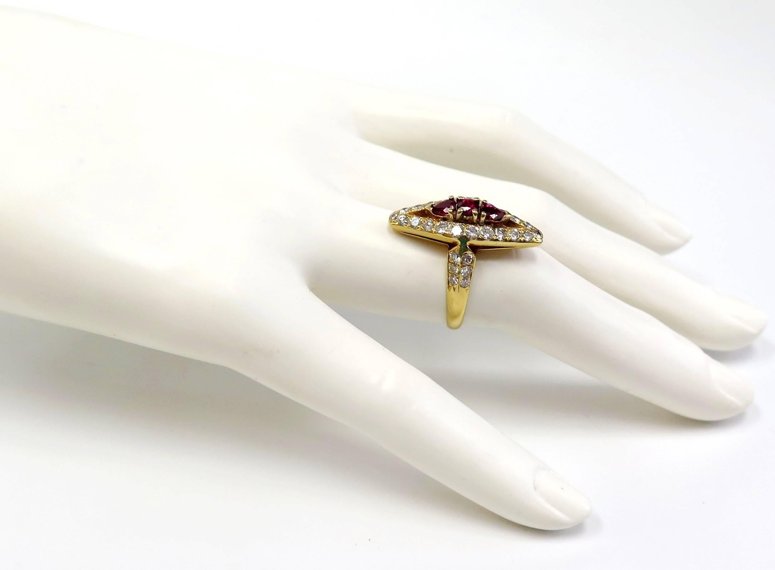 This 1 inch long dinner ring is all lit up with 1.50 Carats of bright-white diamond sparklers enveloping 3 rich vibrant rubies. This 1960s elongated navette-shaped ring is beautifully crafted in 18 Karat yellow gold.  A dramatic vintage