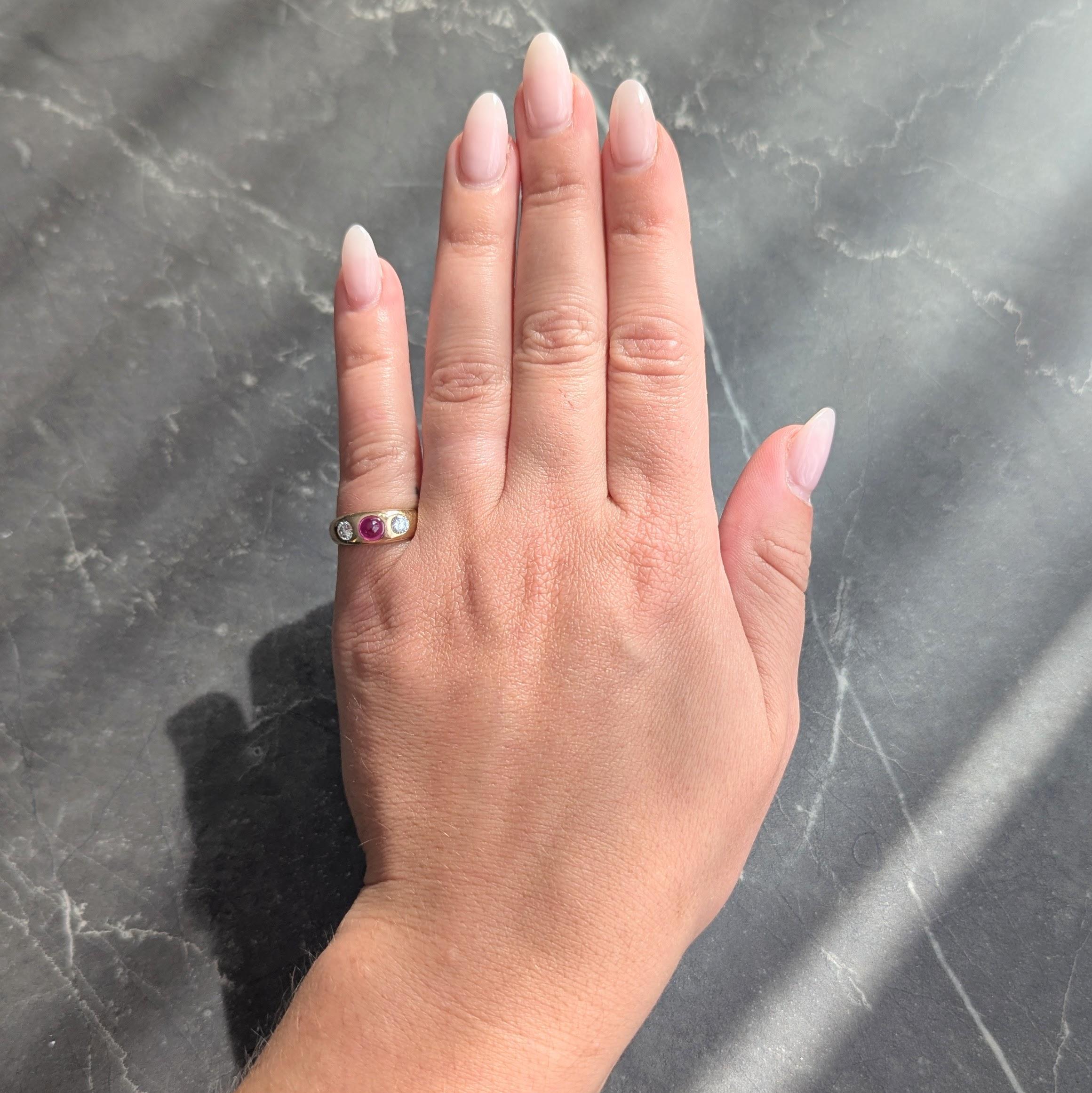 Centering a round ruby cabochon weighing approximately 0.75 carat
Transparent medium purplish red in color and flush set
Flanked by flush set transitional cut diamonds
Weighing approximately 0.35 carat total
G/H color with VS2 clarity
Completed by