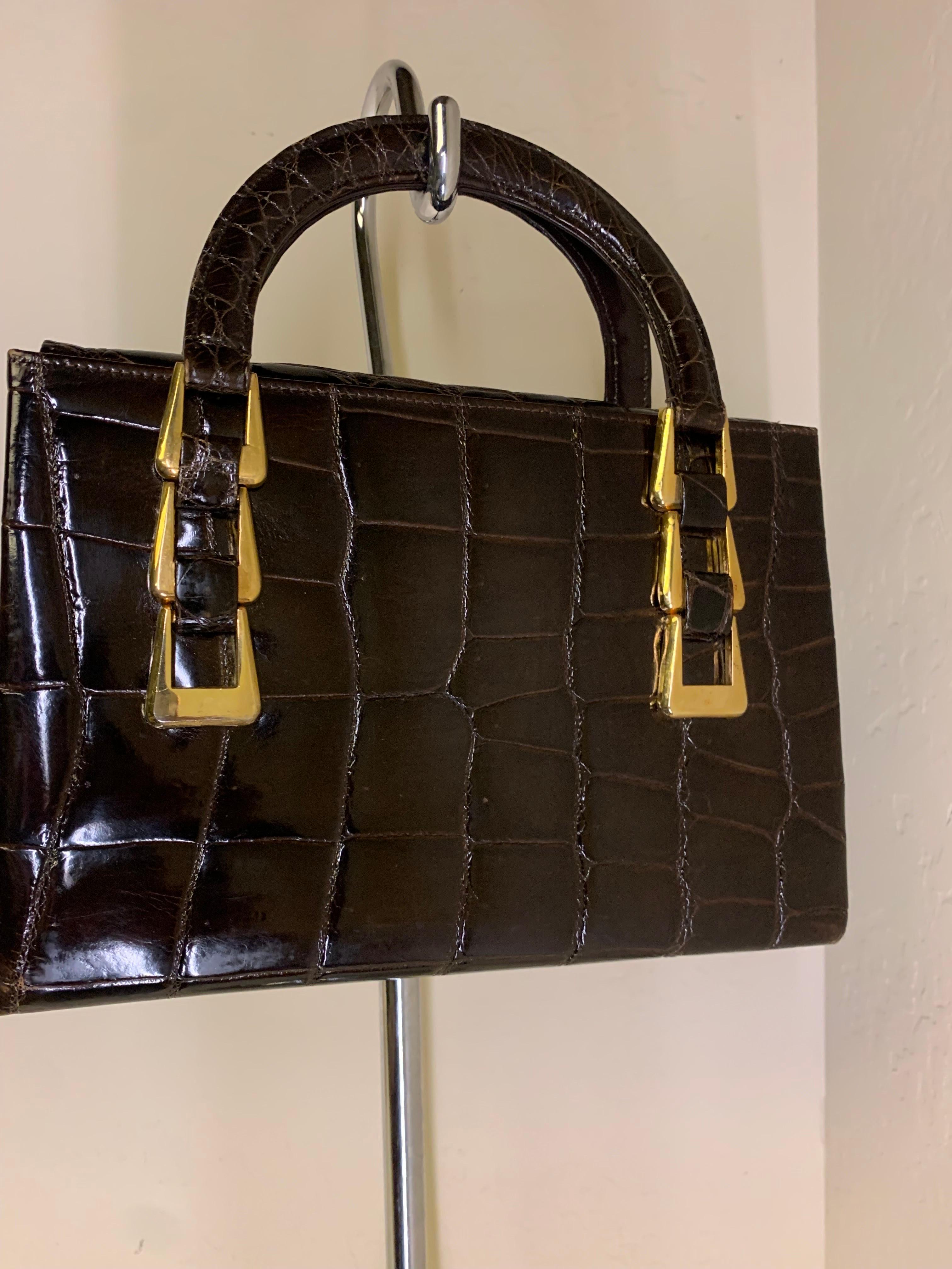 1960s Saks Fifth Avenue deep brown alligator tote bag with triple buckle detail. Made in France. Brown leather lining in pristine condition. Fold-over top piece with tab for easy opening is hidden inside. Small to medium capacity. 