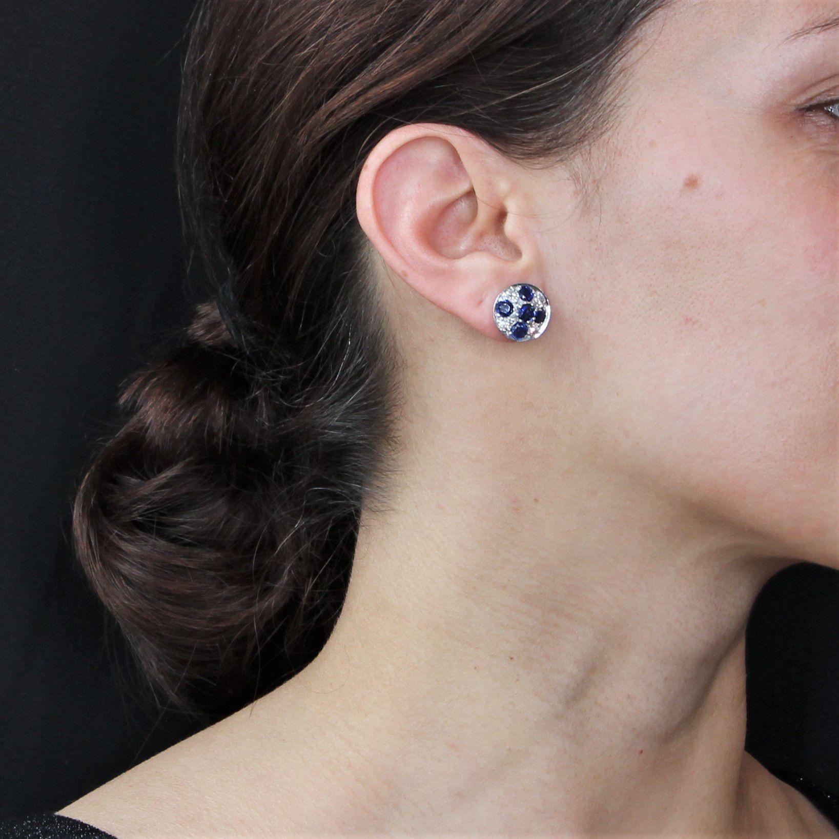 For pierced ears.
Earring in 18 karat white gold.
Round shape, these retro ear studs are each adorned with five blue sapphires enhanced by 8 antique- cut diamonds. The hanging system is butterfly.
Total weight of sapphires : 3 carats