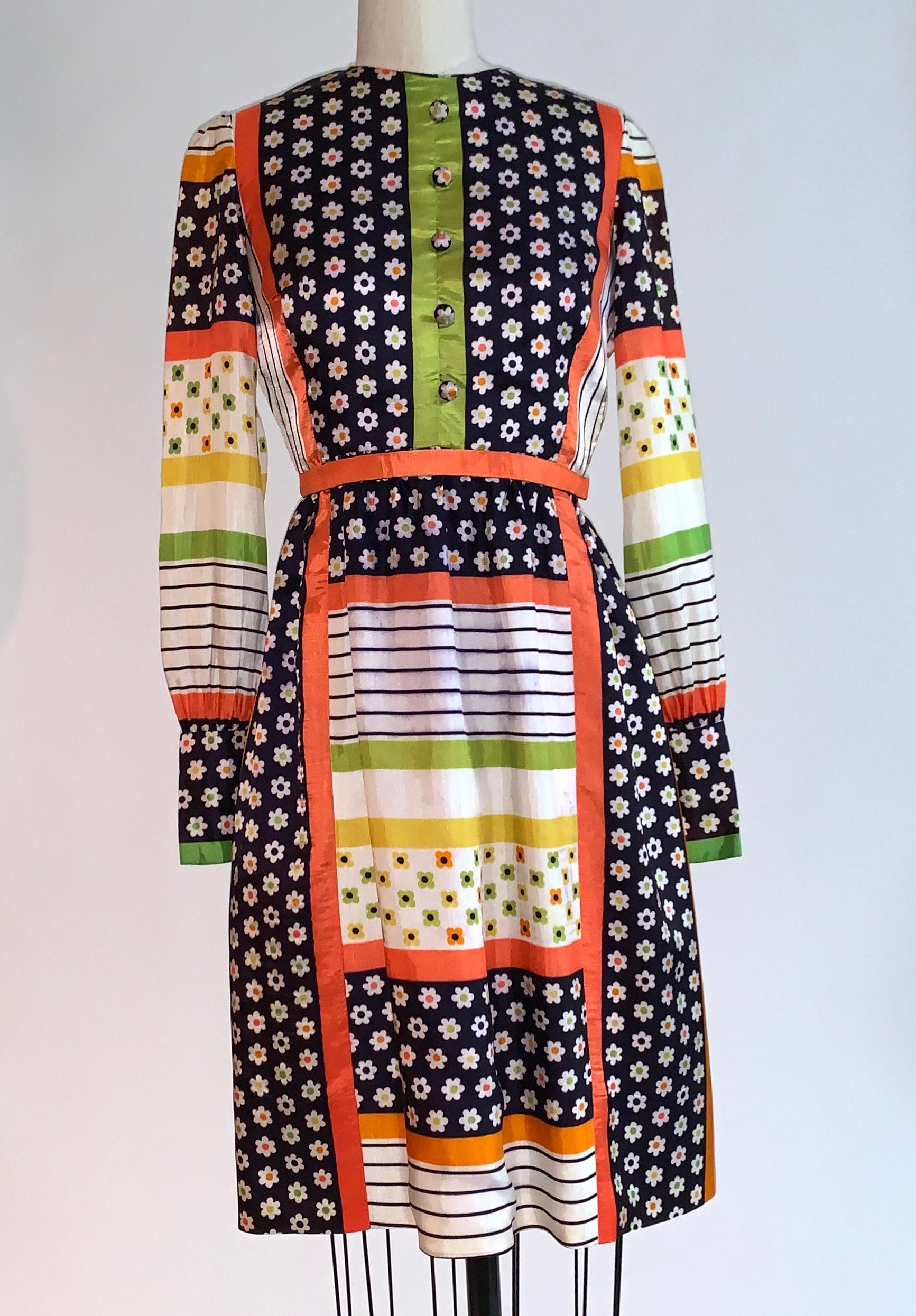Vintage Sarmi 1960's sweet short dress in a retro floral and stripe print. Slightly puffed sleeves with three coordinated cloth covered buttons at each cuff.  Orange belt attached at one side (could be removed) that fastens with snap. Back zip and
