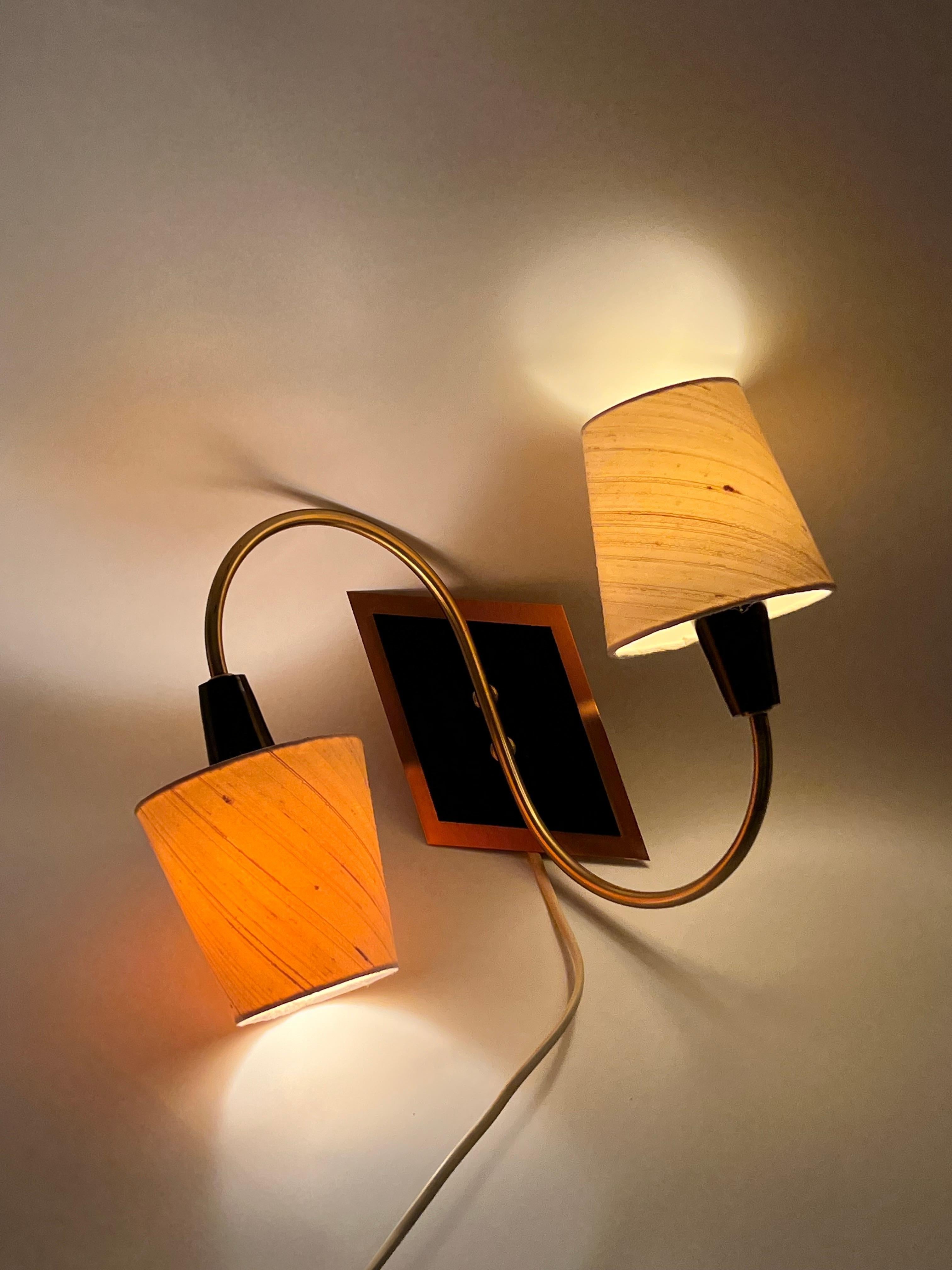 Añade un toque de encanto escandinavo atemporal a tu hogar con esta rara lámpara de pared nórdica primitiva de los años 60 de ASTRA, Noruega. Este candelabro moderno de mediados de siglo tiene pantallas beige de dos colores (pequeñas diferencias de