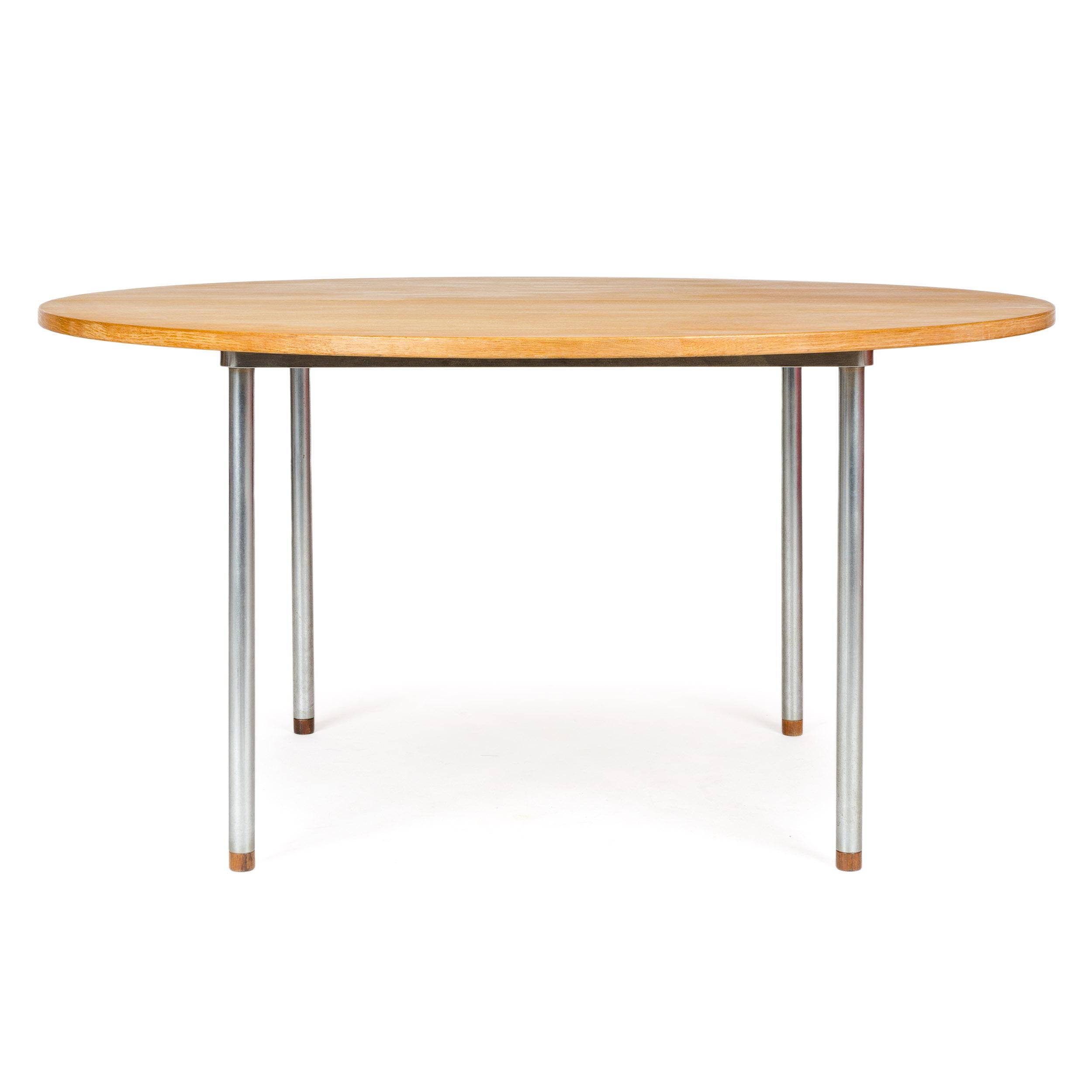 A round extension dining table with oak top set on four tubular chrome legs each tipped with a rosewood insert.