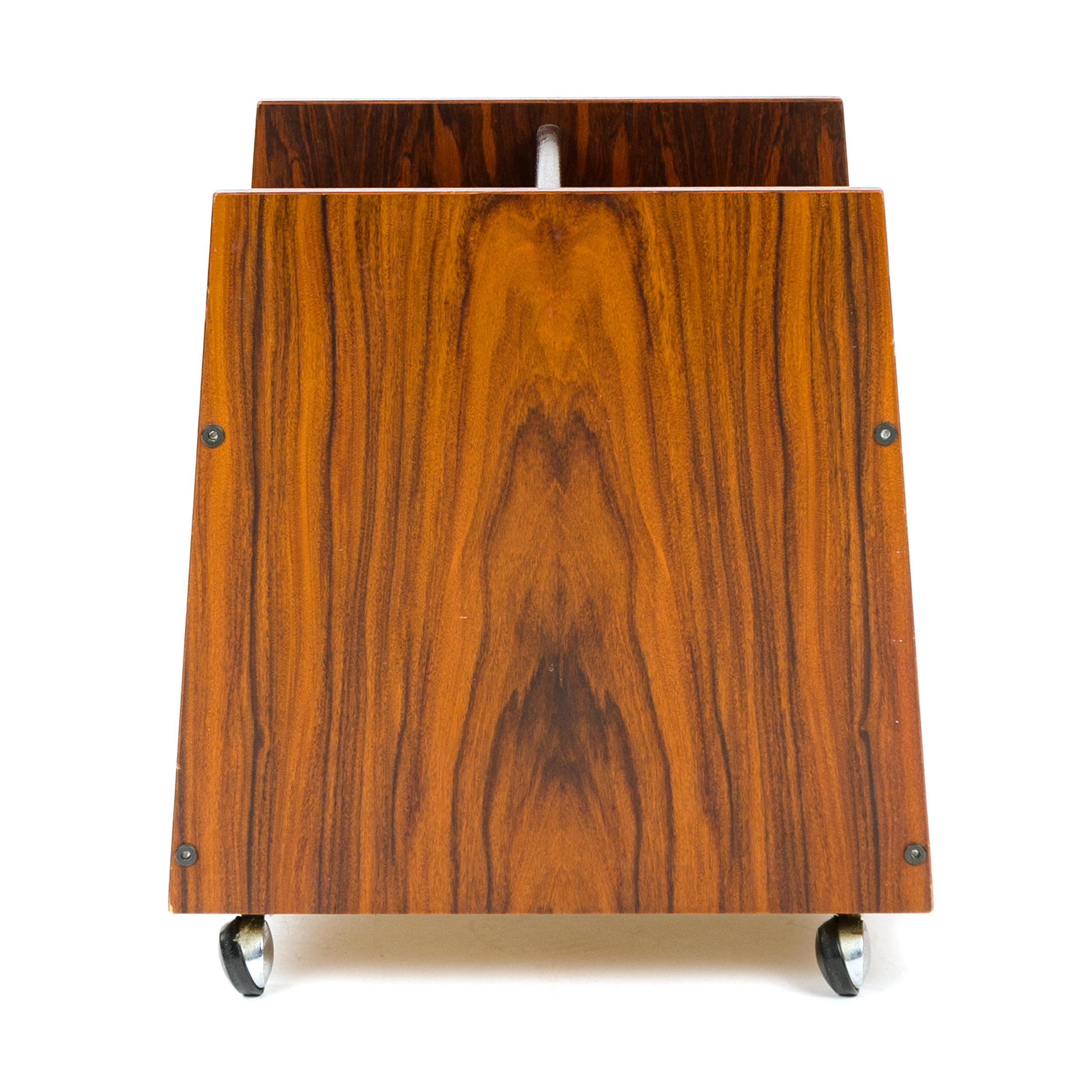 A rolling rosewood magazine caddy on four swivel casters with three divided compartments and a handle for ease of movement.