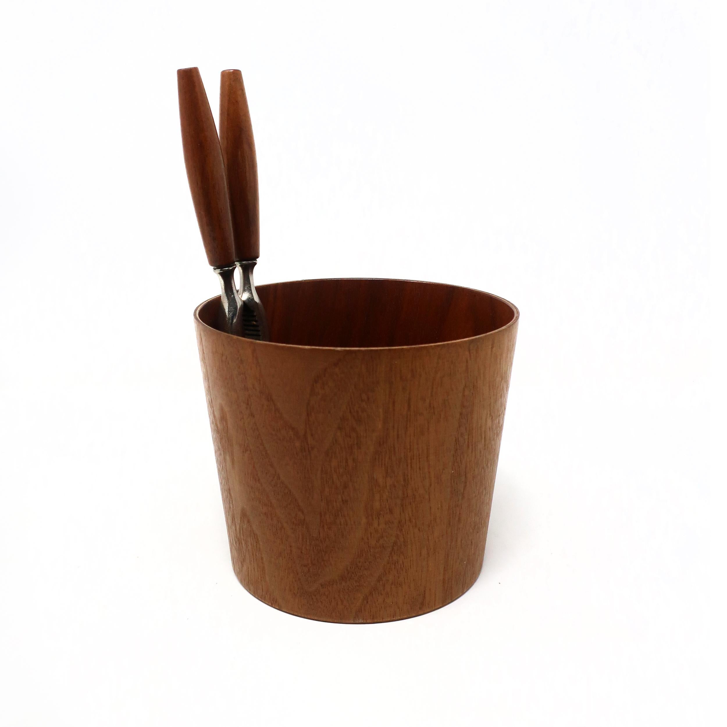 Swedish design house Rainbow Wood Products specialized in streamlined home and office accessories in teak veneer. Designed by Martin Åberg as a nut bowl with nutcracker, this teak receptacle has a delicately flared conical shape and interior pocket