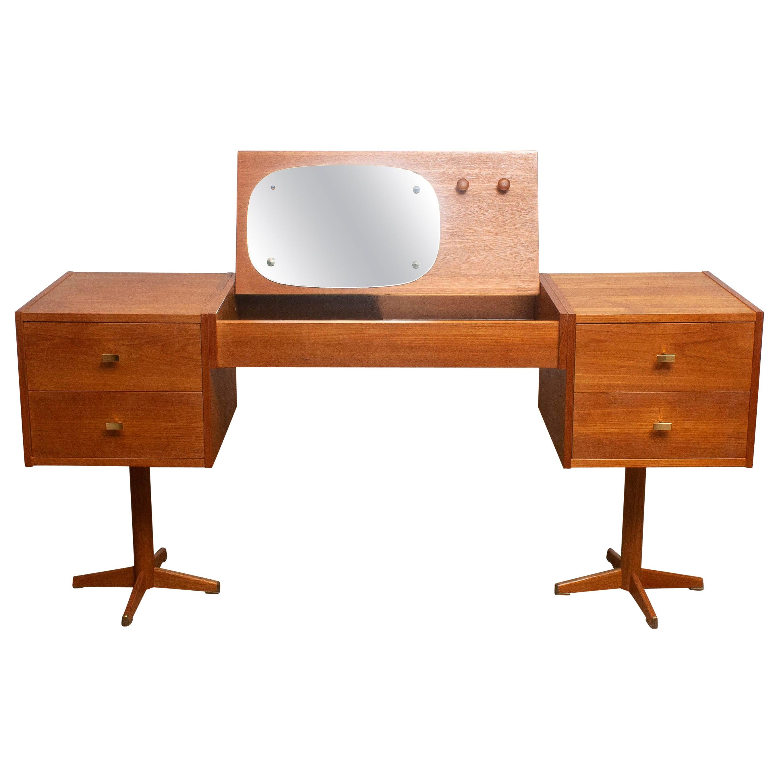 Beautiful vanity desk made in Scandinavian, Sweden.
This piece is in a very nice and good condition.
It is made of teak with four drawers with brass handles and in the top a flap with storage space and mirrors and hanging knobs.
The legs are