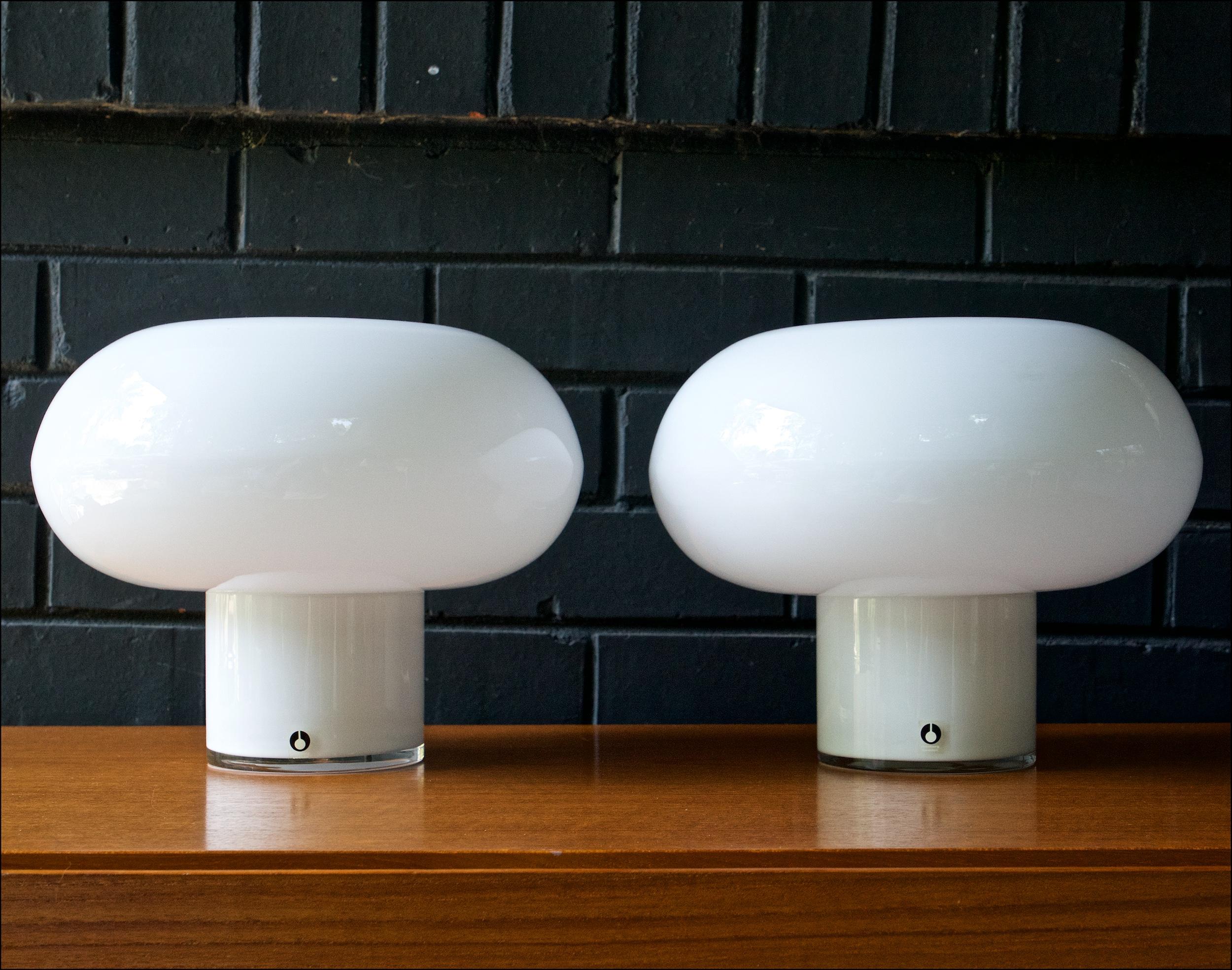 Cased white polished glass globe table lamps by Pukeberg of Sweden. The ellipsoid spherical shade sits on top of a glass cylinder for a minimalist profile. Wired for US and in working order, an in-line cord switch. A pair of wonderful translucent